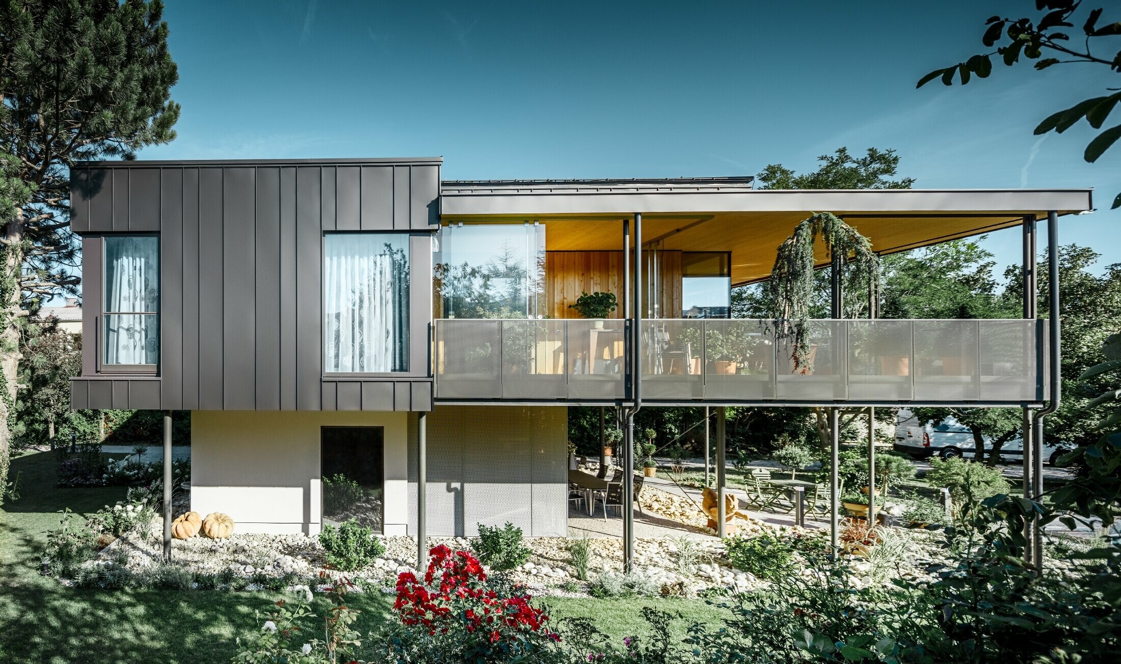 Maison individuelle moderne à l’esthétique arboricole au cœur d’un grand jardin planté de nombreux arbres — Façade PREFA dépouillée à joints angulaires de couleur gris noir