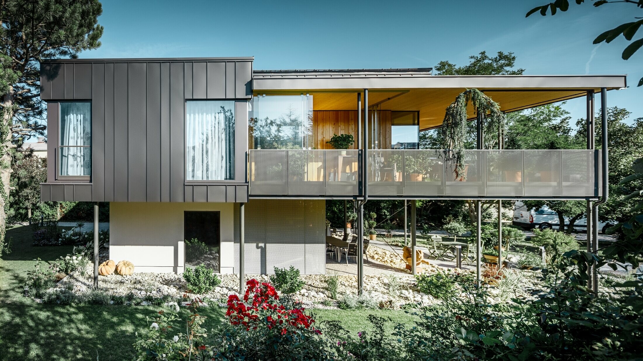 Casa unifamiliare moderna, simile a una casa sull'albero circondata da un grande giardino con tanti alberi e una facciata in aggraffatura angolare in nero opaco di PREFA 