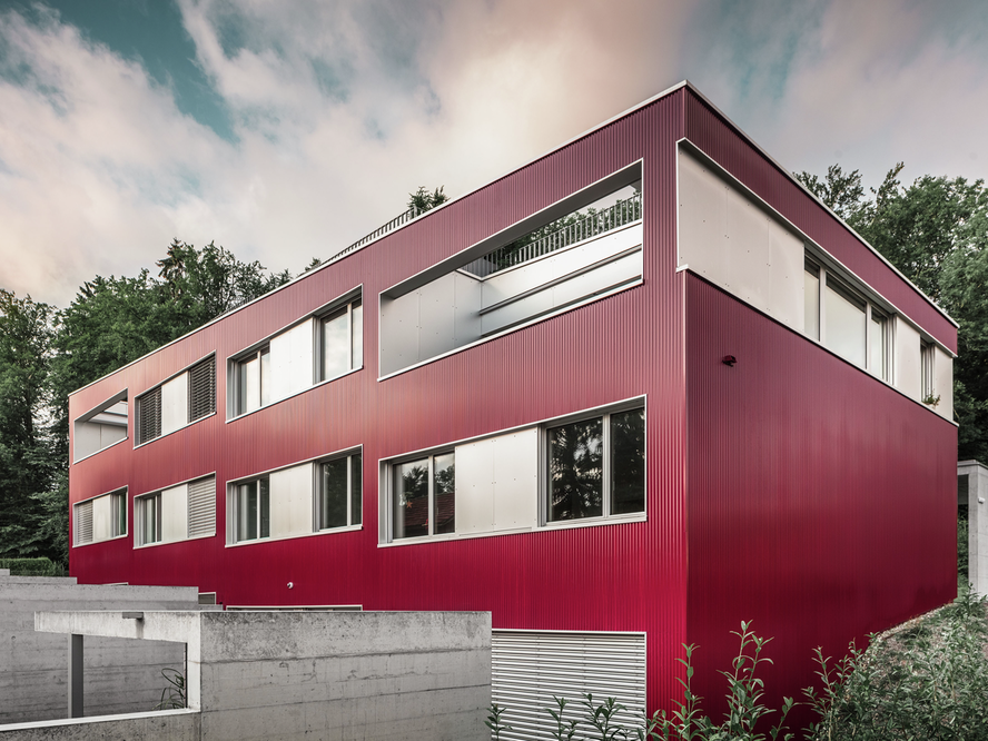 Vue extérieure latérale du bâtiment résidentiel sur le lac de Zurich en Suisse, revêtu d'un profilé PREFA sinus de couleur bordeaux