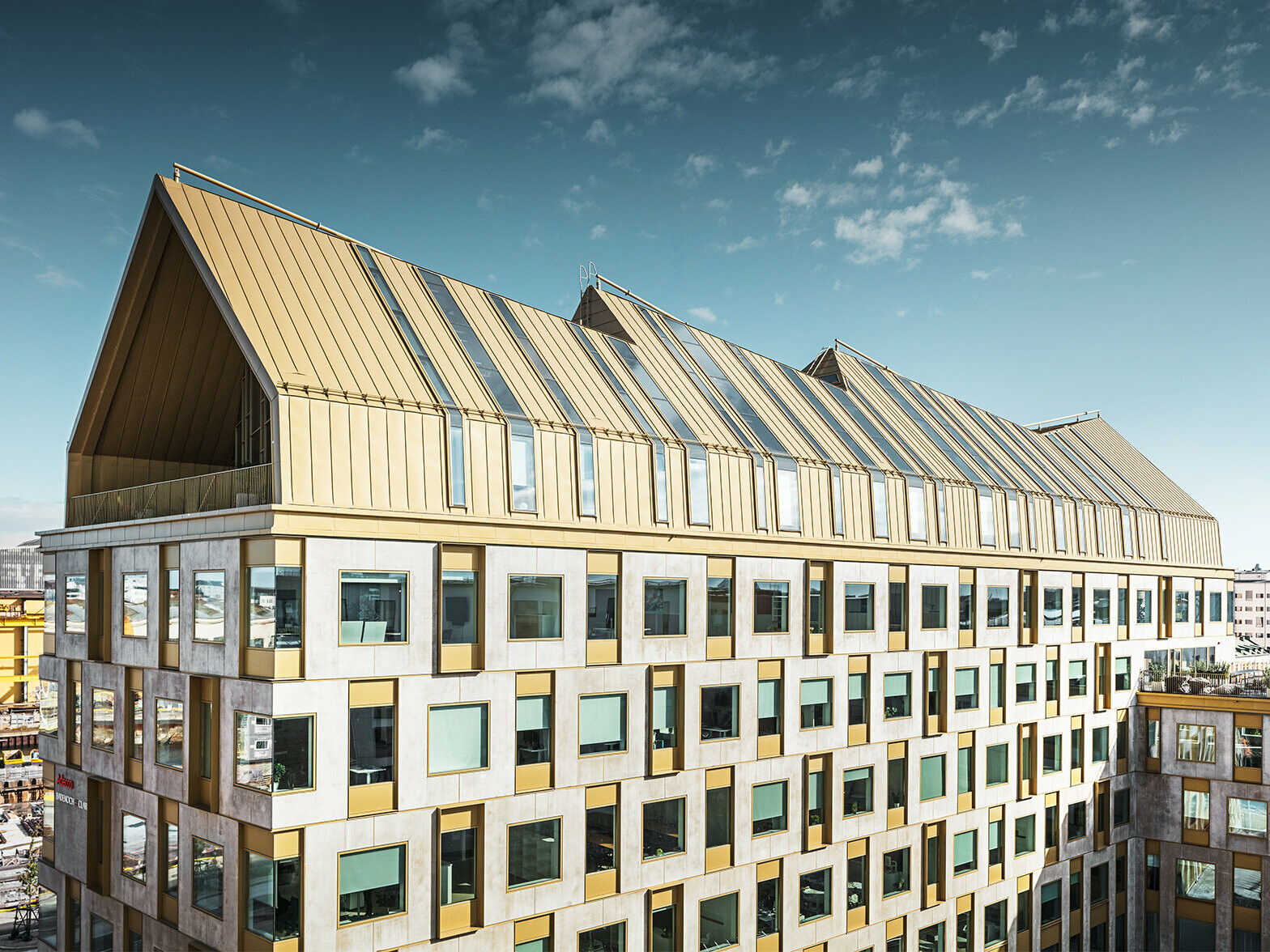 seitliche Frontansicht des Kontorgebäudes in Schweden bei Sonnenschein eingedeckt mit dem Dachsystem PREFALZ in der Sonderfarbe Jaisalmer Gold