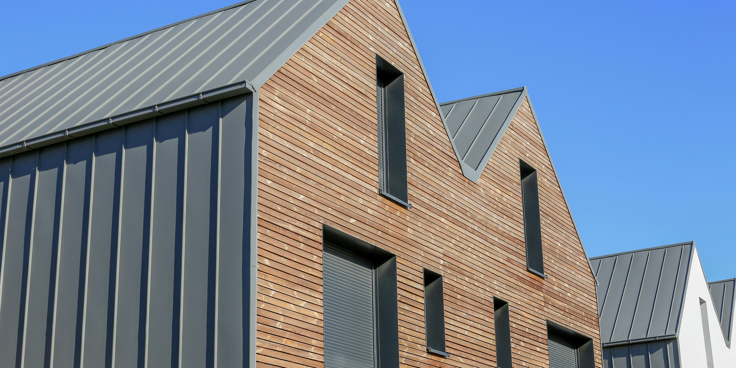 Le joint debout PREFALZ en gris souris s'étend sur les façades et les toits à pignon d'un lotissement mitoyen à Mundolsheim. Les coques uniformes du bâtiment en aluminium créent une image globale harmonieuse.
