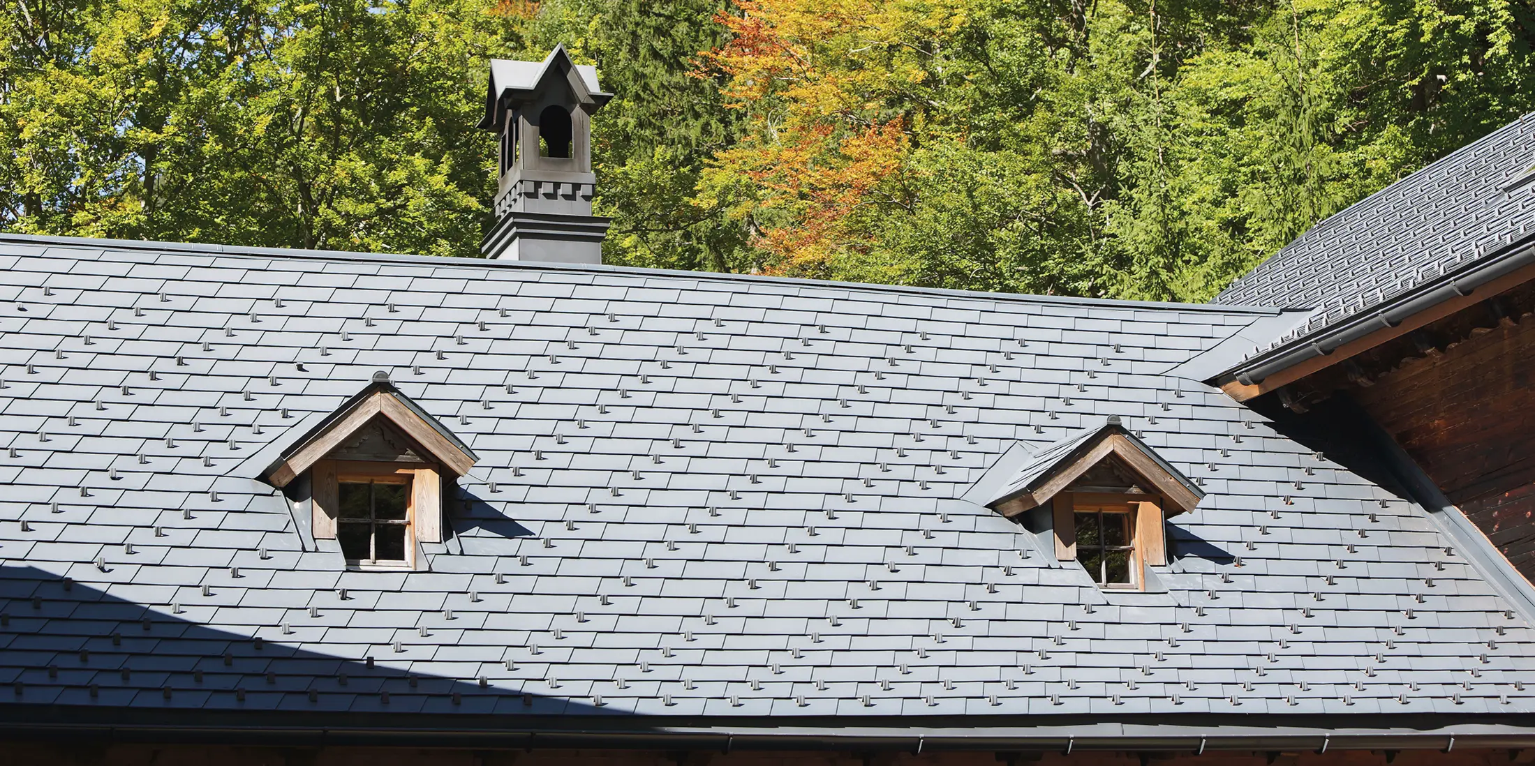 Detailaufnahme des Daches des Rothschildhauses in Langau bei Gaming mit PREFA Dachschindeln in Anthrazit, begleitet von traditionellen Architekturmerkmalen und Natur.