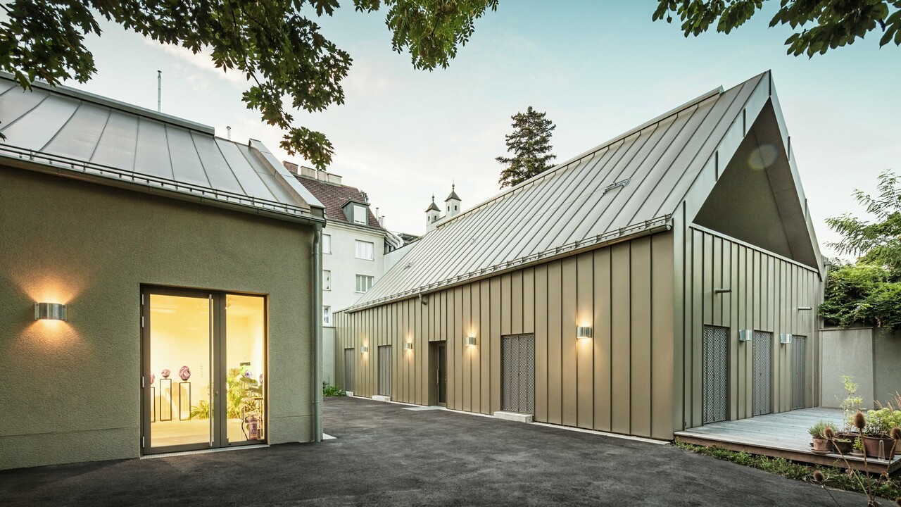 Vue latérale du Studio Comploj à Vienne avec une façade en aluminium PREFALZ en P.10 bronze Prefa. L'ensemble moderne composé d'un atelier de soufflage de verre, d'une galerie et d'un espace de vie allie artisanat et architecture.