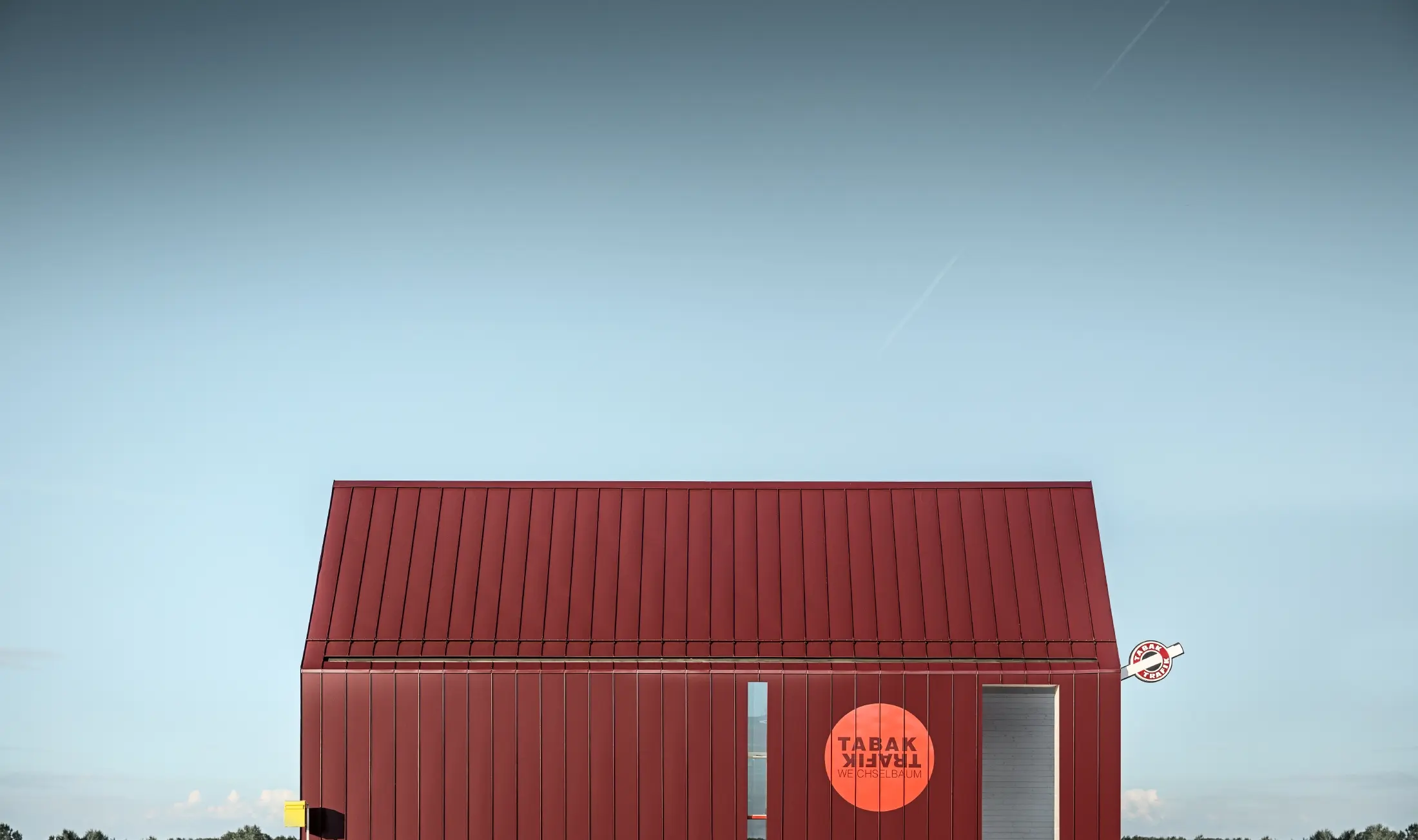 Bureau de tabac moderne au toit à deux versants sans saillie de façade — Enveloppe en aluminium PREFA à joints debout et joints angulaires rouge-noir (couleur spéciale)