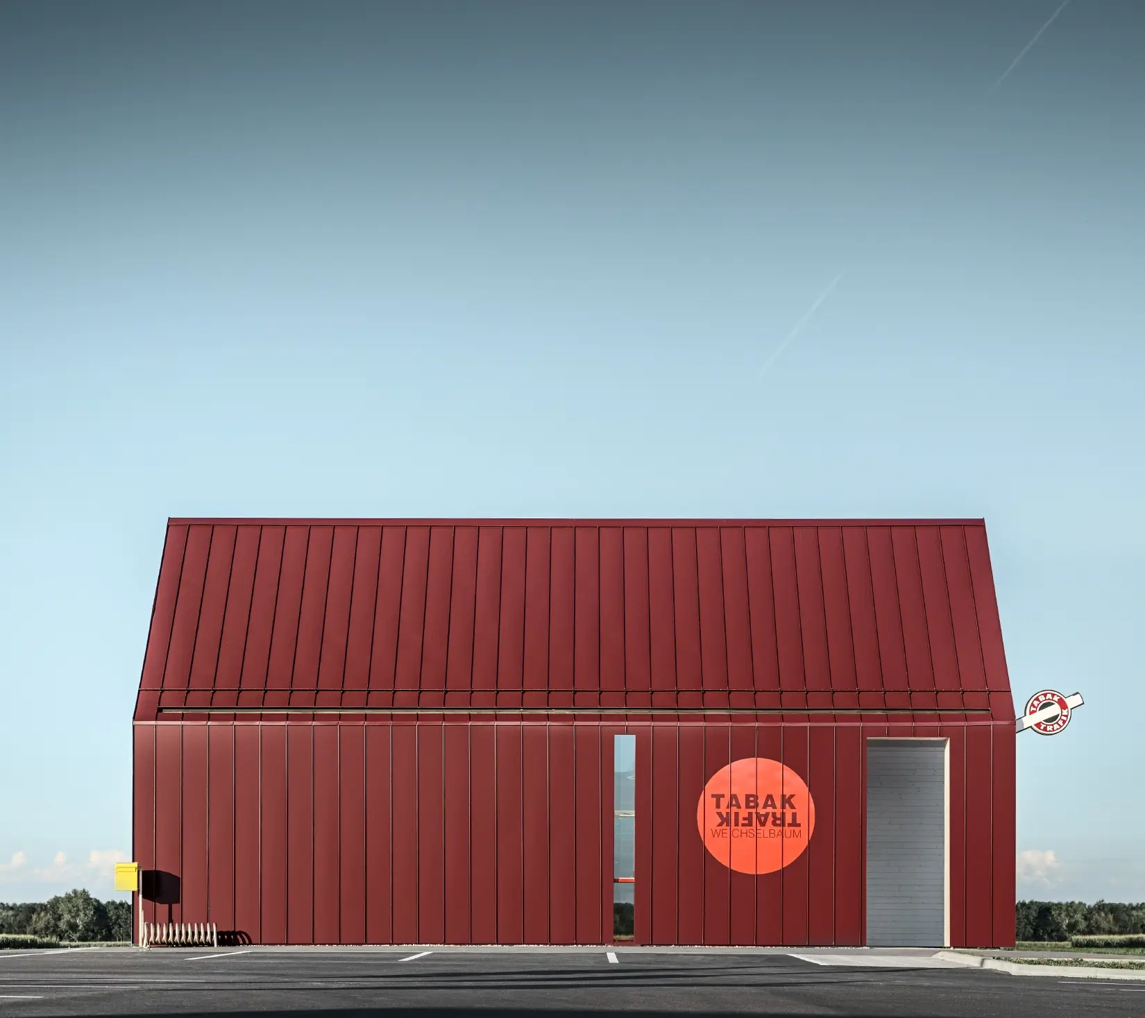 Bureau de tabac moderne au toit à deux versants sans saillie de façade — Enveloppe en aluminium PREFA à joints debout et joints angulaires rouge-noir (couleur spéciale)
