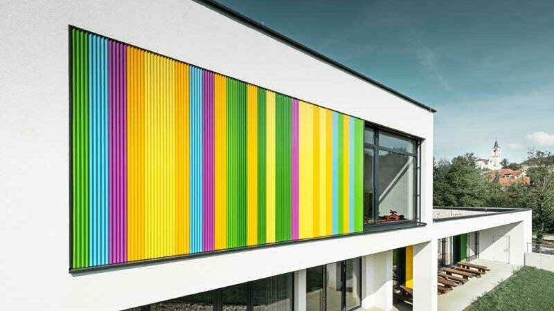 École maternelle moderne présentant des détails ornementaux colorés sur la façade grâce au profil triangle PREFA