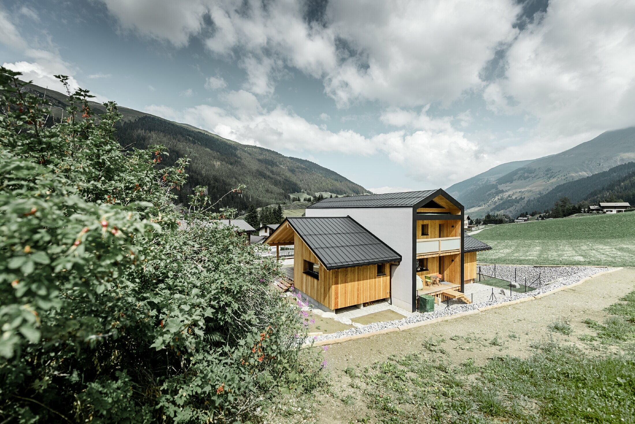 Cette maison individuelle donne l’impression que 2 maisons sont superposées selon un angle de 90°. Le toit est recouvert de Prefalz couleur noir et la façade est partiellement habillée de bois.