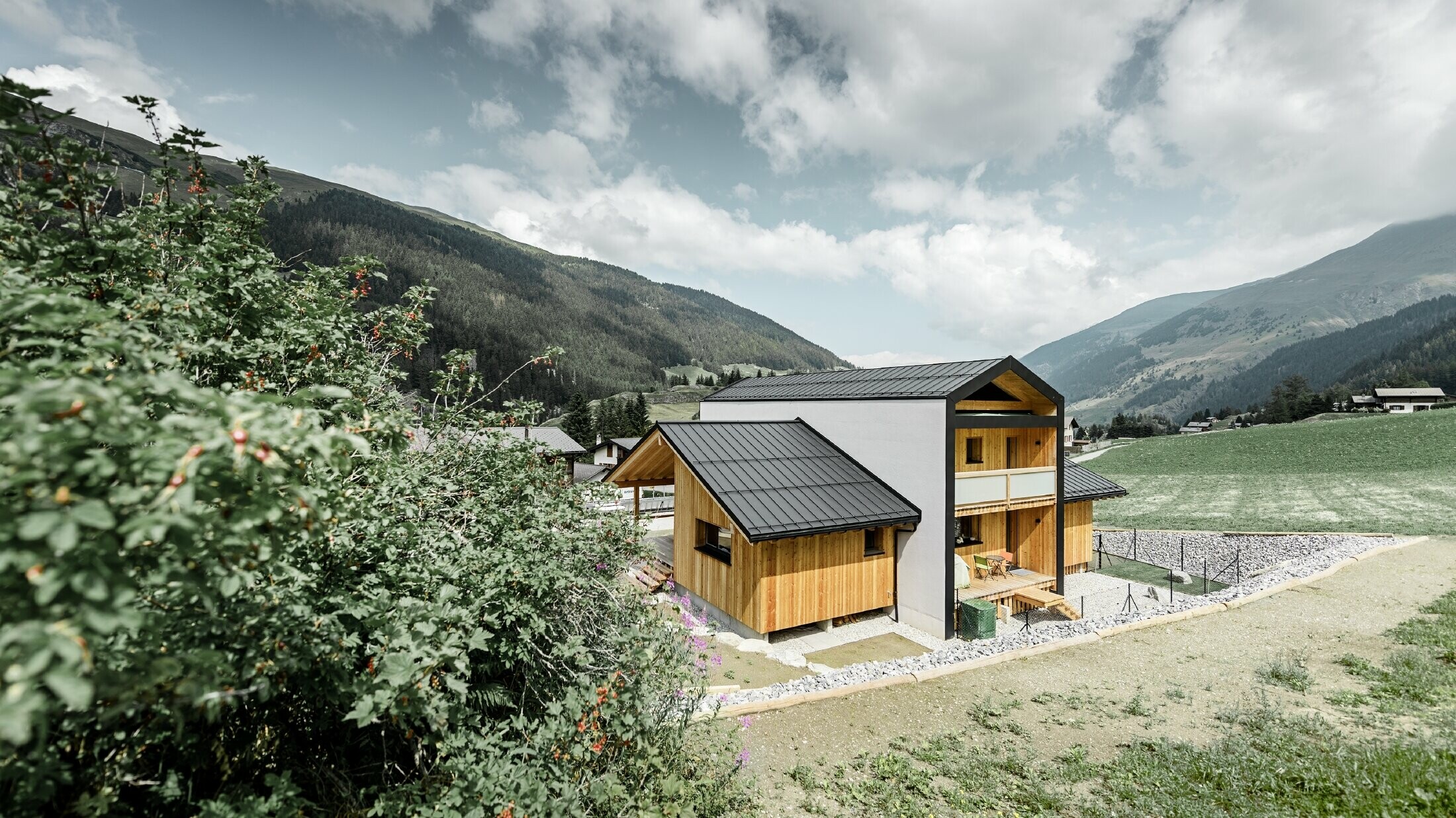 Dieses Einfamilienhaus wirkt, als wären 2 Häuser im 90° Winkel übereinander gestellt worden. Das Dach ist mit Prefalz in Schwarz und die Fassade zum Teil mit Holz verkleidet.