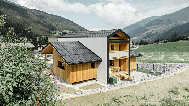 Dieses Einfamilienhaus wirkt, als wären 2 Häuser im 90° Winkel übereinander gestellt worden. Das Dach ist mit Prefalz in Schwarz und die Fassade zum Teil mit Holz verkleidet.