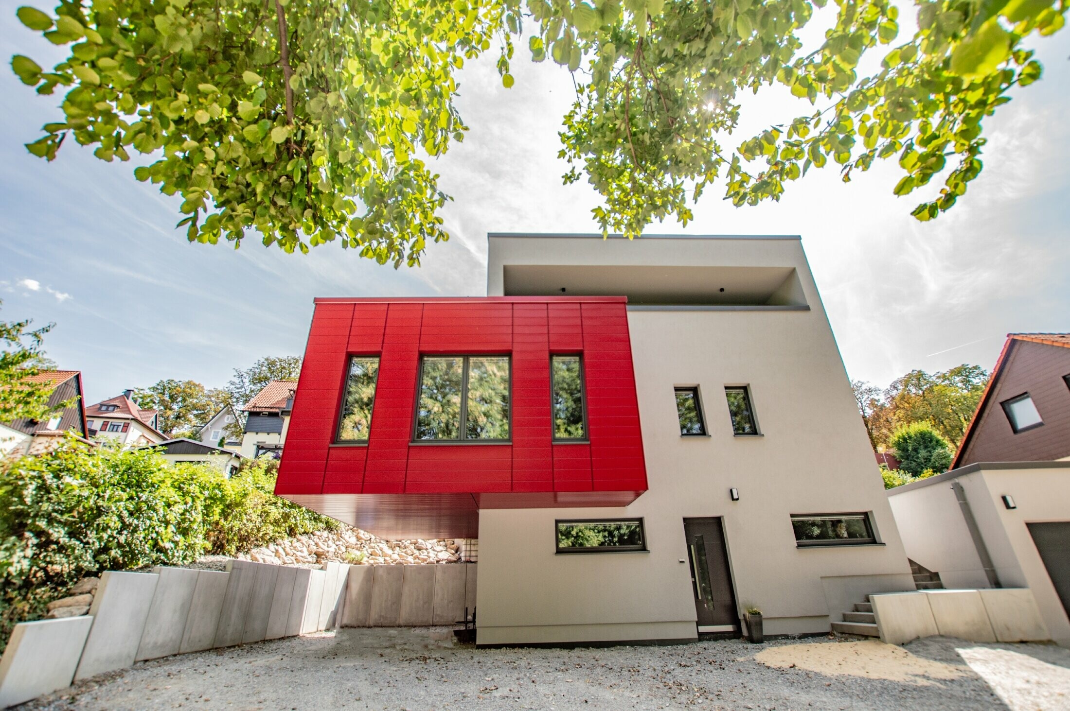 Parte aggettata dell'edificio rivestita con doghe PREFA in rosso rubino. Ampio bovindo di colore rosso che risalta sulla facciata bianca.