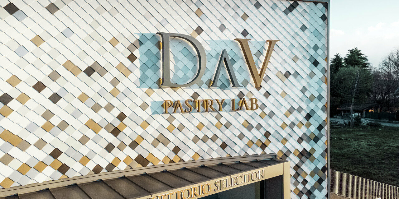 Bâtiment d'entreprise DAV Pastry Lab de Bergame avec façade mouchetée avec le losange de façade dans les couleurs P.10 brun, bronze, P.10 gris sombre, mayagold, aluminium naturel, P.10 blanc Prefa et P.10 blanc pur. 