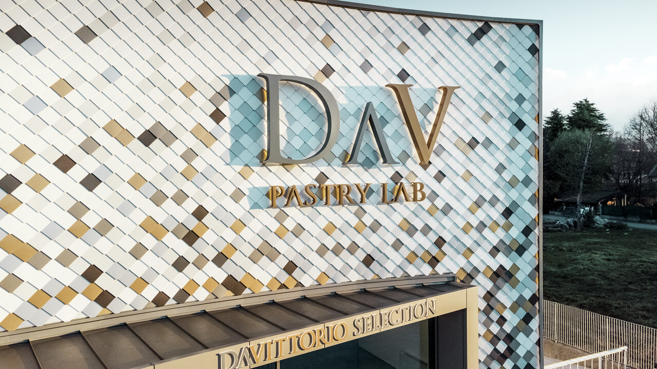 L’edificio dell'azienda DAV Pastry Lab di Bergamo con la scaglia per facciata nei colori P.10 marrone, bronzo, P.10 grigio scuro, mayagold, alluminio naturale, P.10 bianco PREFA e P.10 bianco puro 