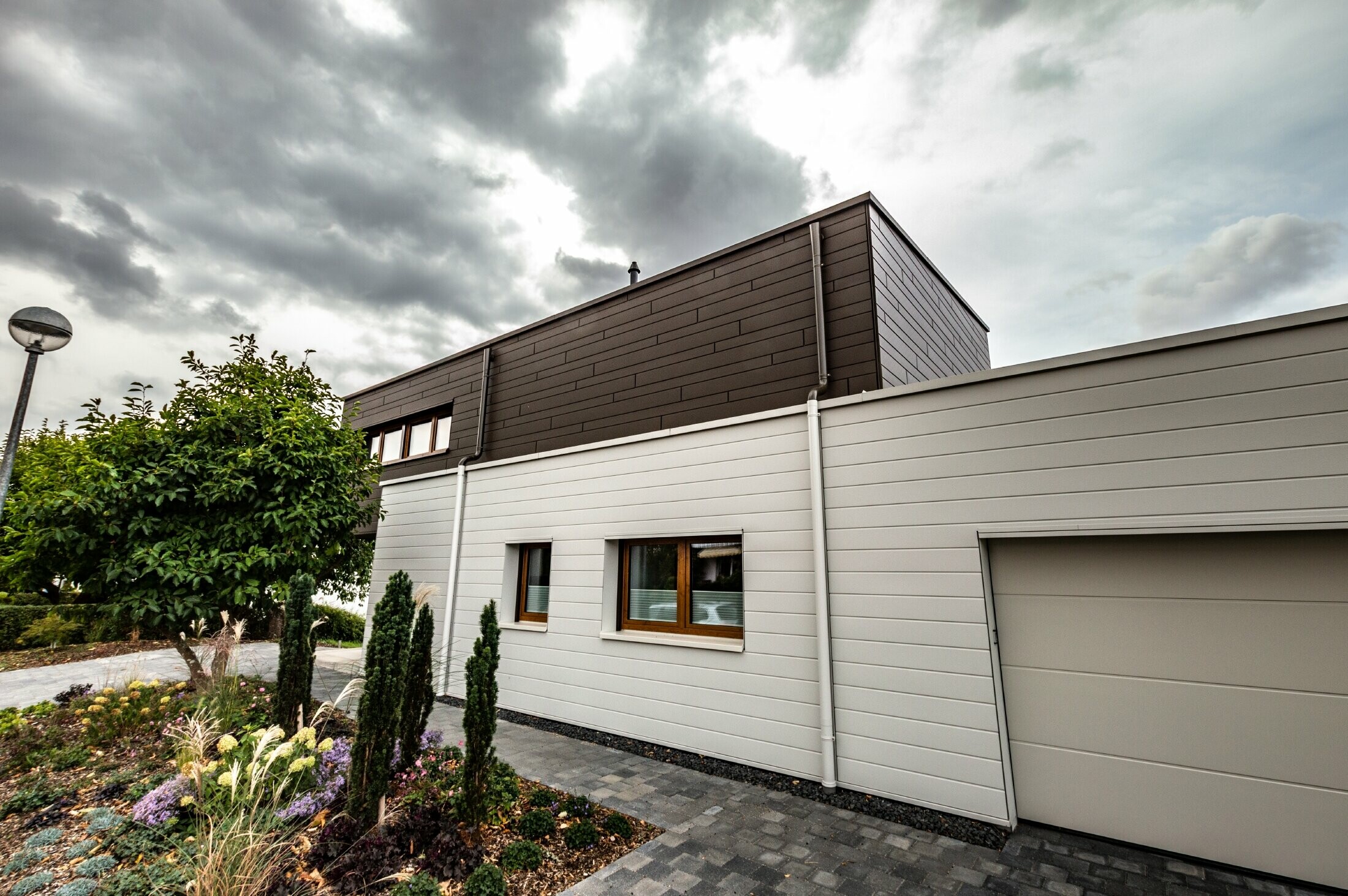 Habillage de façade d’un garage avec les Sidings PREFA à l’horizontale en blanc, avec embranchement d’évacuation.