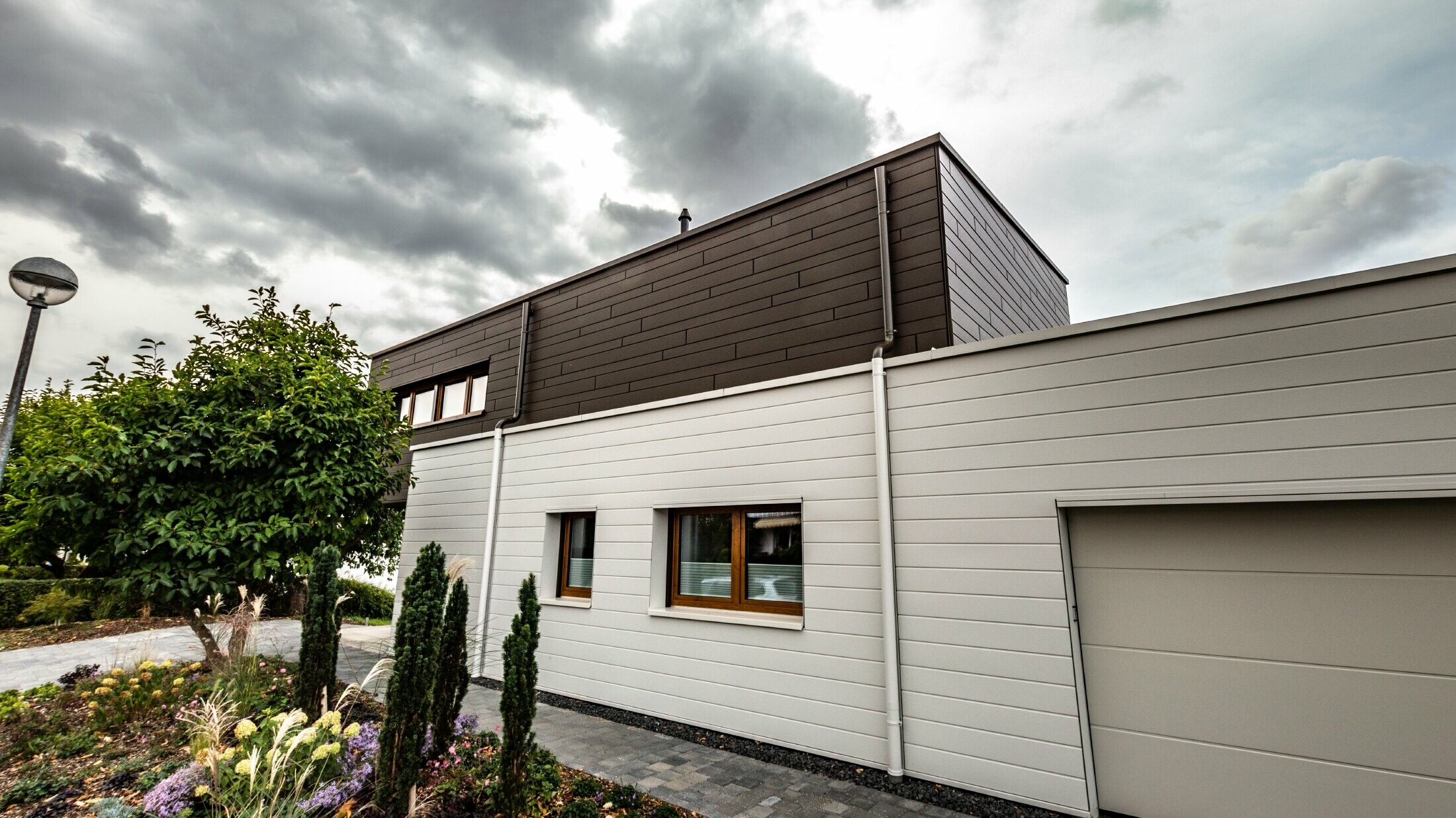 Fassadenverkleidung einer Garage mit den PREFA Sidings horizonal in Weiß, mit Speiereinmündung.