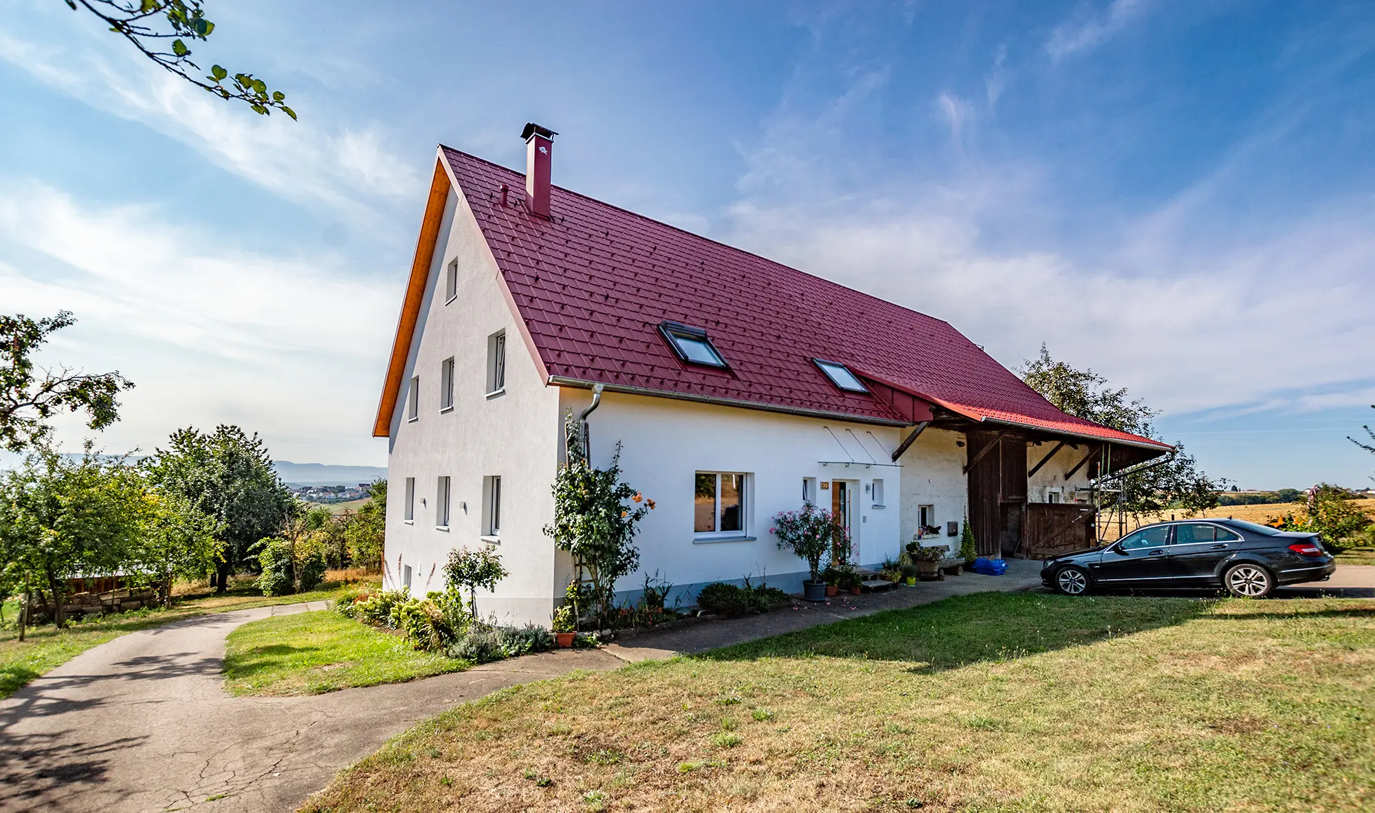 Ancienne fermette à la campagne joliment rénovée avec la tuile PREFA couleur rouge oxyde.