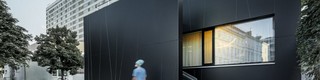 Frontalansicht der zentralen Notaufnahme der Klinik in der Juchsgasse in Wien wurde mit PREFABOND Aluminium Verbundplatten in der Farbe schwarzgrau verkleidet. Im Bild ist eine Krankenschwester zu sehen.