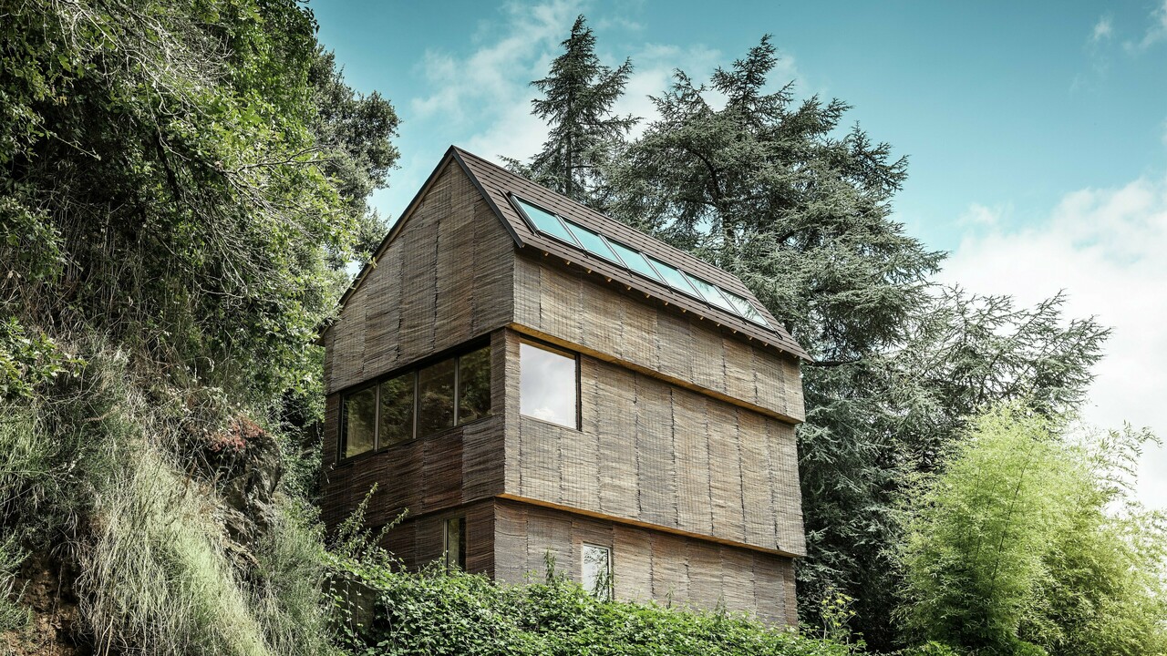 Maison dans l'ouest de la France avec toiture en bardeaux PREFA couleur P.10 brun noisette, située sur une colline escarpée - design moderne avec façade en bois de saule et toiture économe en énergie.