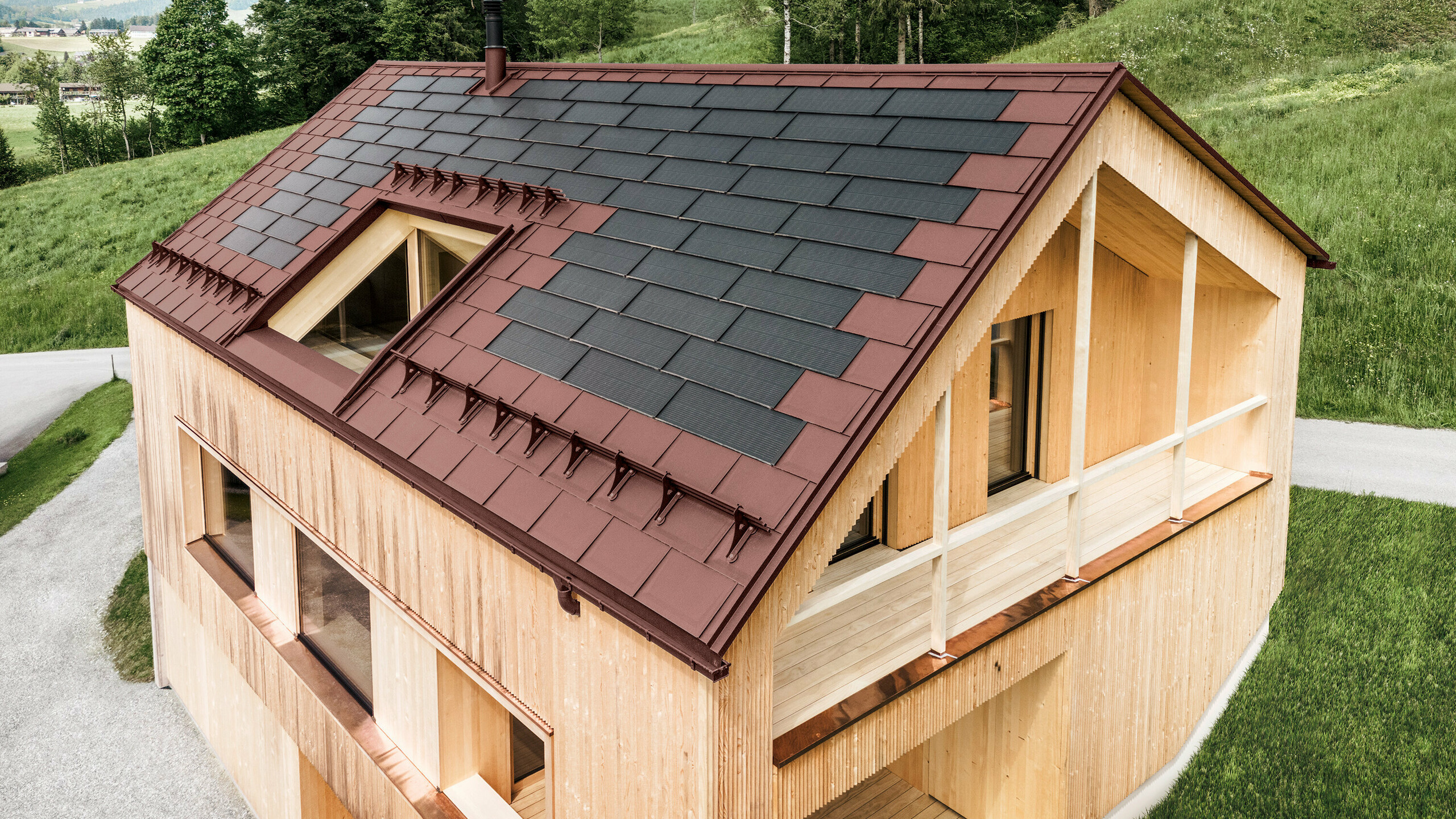 Einfamilienhaus im österreichischen Ort Egg mit der PREFA Solardachplatte und der Dachplatte R.16 in Oxydrot, kombiniert mit einer Holzfassade