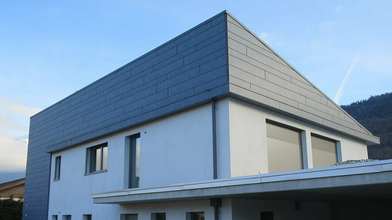 Hier sehen Sie die Seitenansicht eines Neubau in Monthey mit PREFA Siding steingrau