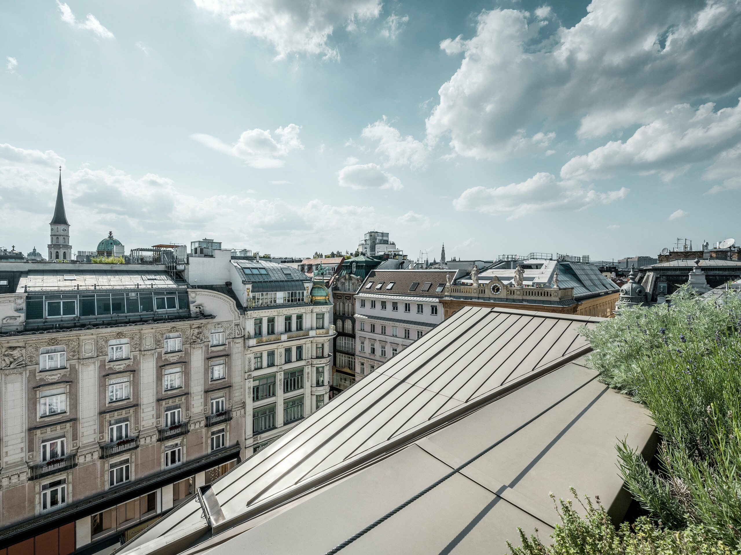 Vue large sur les toits de Vienne, avec à gauche les bandes Prefalz à l’élégante couleur bronze de l’hôtel Rosewood Vienna.