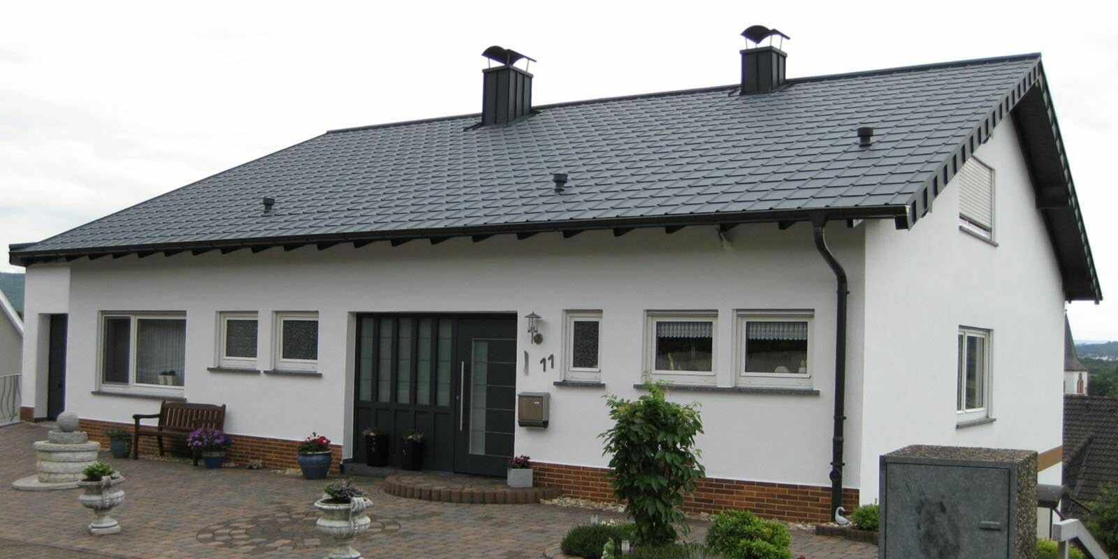Maison individuelle avec toit à deux pans simple, après la rénovation de toiture à l’aide de tuiles PREFA