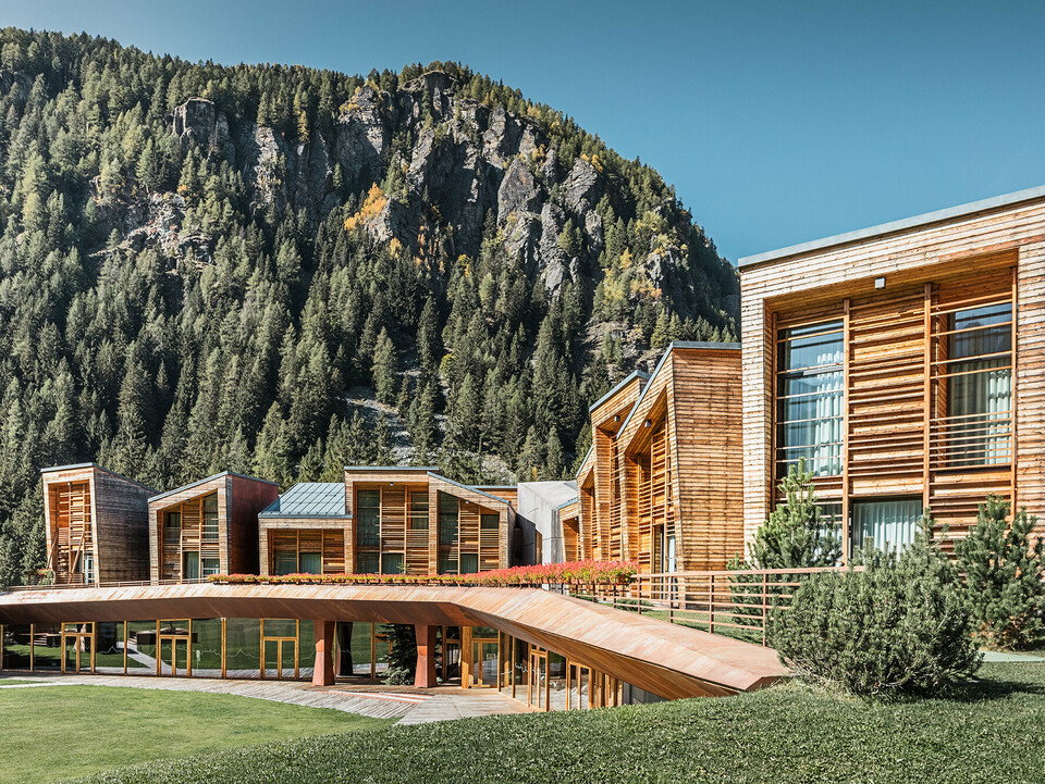 Seitenansicht des oberen und unteren Bereichs des CampZero Resorts im Aostatal mit Gebirge im Hintergrund.