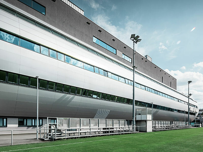 Immagine dell'Allianz Stadion di Vienna dal campo di allenamento; il tubo che conduce all'interno dello stadio è rivestito con il pannello composito in alluminio PREFA in silver metallizzato.