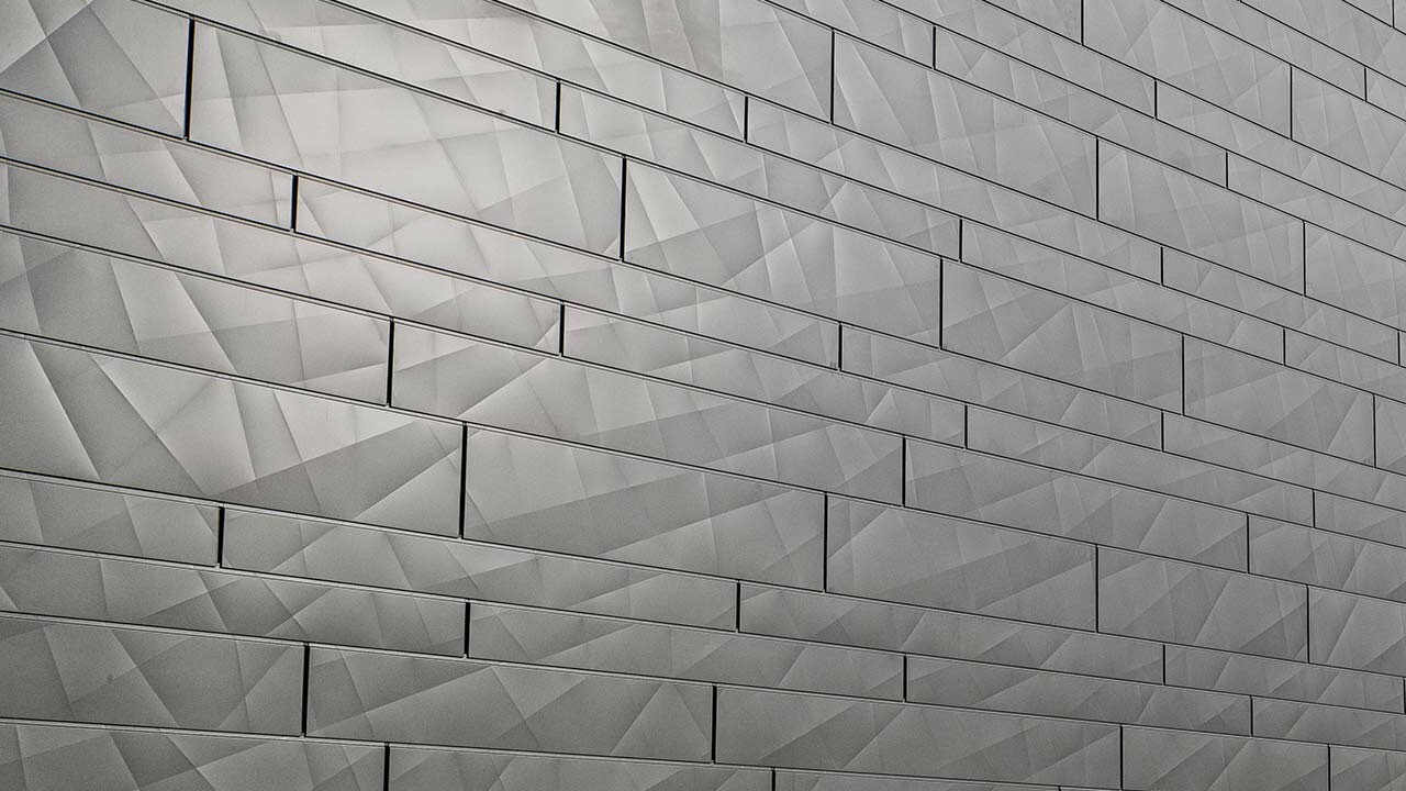 Fassadenfläche mit Alufassade, hinterlüftet ausgeführt, mit dem neuen Fassadenpaneel Siding.X von PREFA; Die Paneele sind gekantet und mit unterschiedlichen Breiten an der Fassade montiert, dadurch ergibt sich ein interessantes Fugenbild.