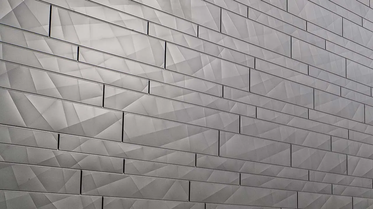 Fassadenfläche mit Alufassade, hinterlüftet ausgeführt, mit dem neuen Fassadenpaneel Siding.X von PREFA; Die Paneele sind gekantet und mit unterschiedlichen Breiten an der Fassade montiert, dadurch ergibt sich ein interessantes Fugenbild.