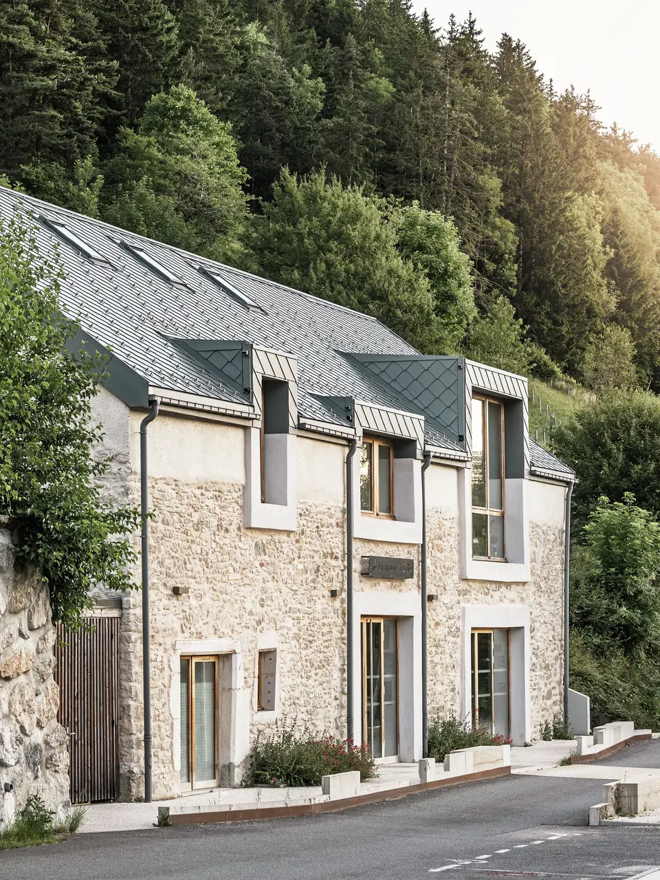 Il fienile restaurato “La Grange à Gaby” a Engins, in Francia. L'edificio combina la tradizionale muratura in pietra con un moderno tetto in alluminio PREFA composto da scaglie di 29 × 29 cm. La ristrutturazione combina metodi di costruzione storici con un'architettura contemporanea e materiali sostenibili che attirano l'attenzione.