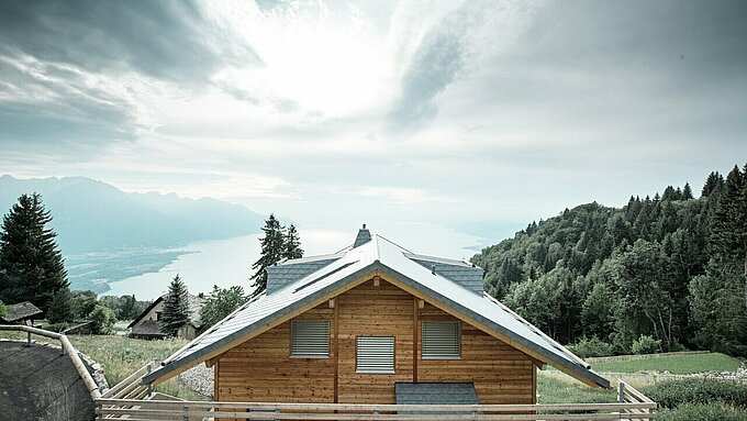 Moderne Holz-Lodge in Veytaux mit widerstandsfähigem PREFA Dach aus Aluminium-Dachschindeln in Steingrau – stilvolle Dachgestaltung mit Ausblick über den Genfersee.