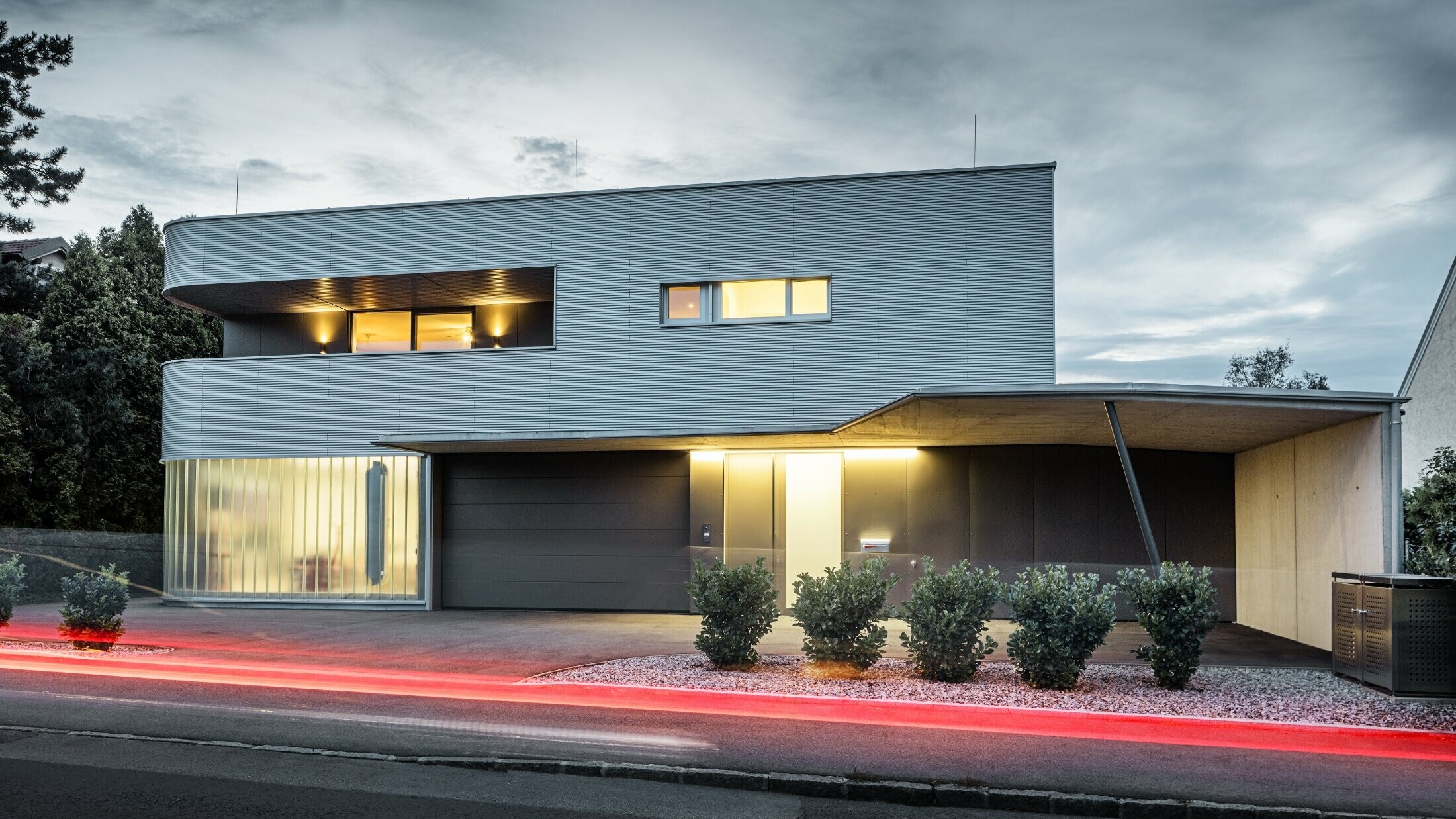 Bâtiment résidentiel moderne avec façade couleur aluminium naturel de profil sinus PREFA, avec garage, dans la lumière du soir