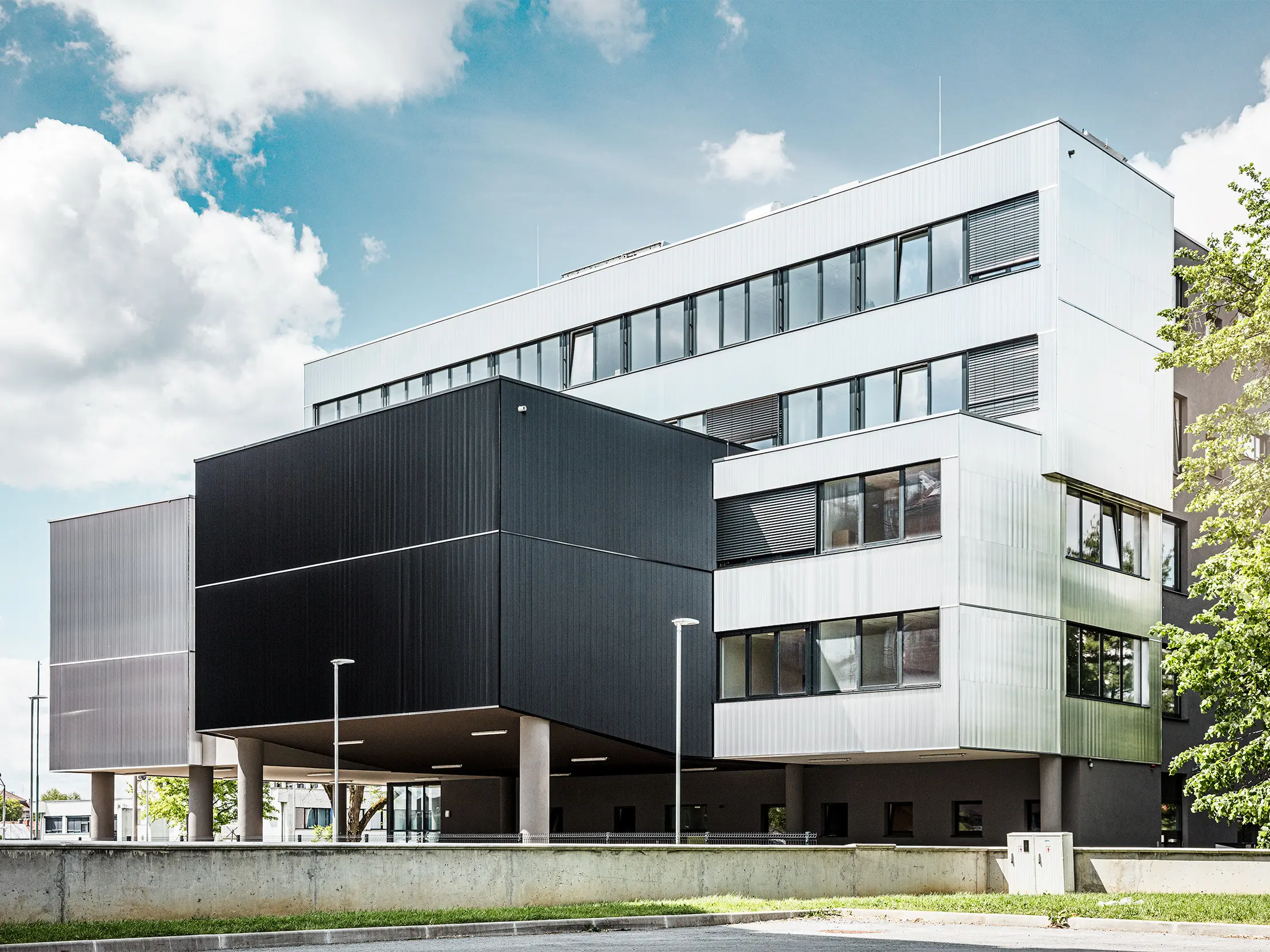 Vue latérale de l'école de musique à Bjevolar, avec une façade PREFA moderne en profil triangle. Sa façade noire en aluminium brut et ses formes géométriques forment un ensemble stylistique à la fois minimaliste et remarquable.