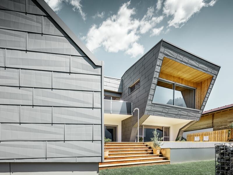 La facciata di questa casa monofamiliare è stata realizzata combinando i pannelli in alluminio PREFA in P.10 grigio chiaro con elementi in legno