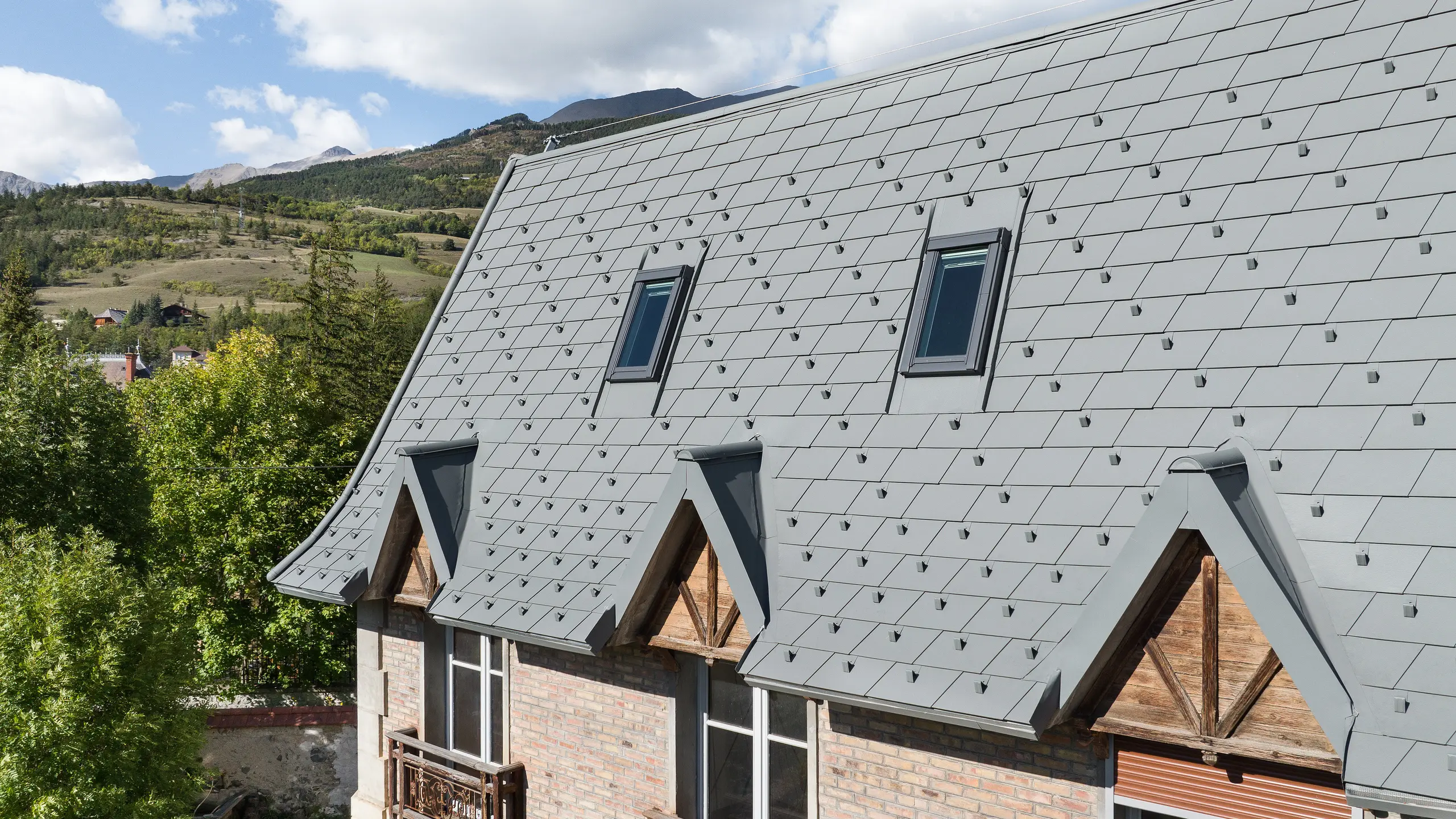 La vaste toiture d'une propriété à Barcelonnette, en France, a été rénovée avec le bardeau de toiture PREFA en P.10 gris souris.