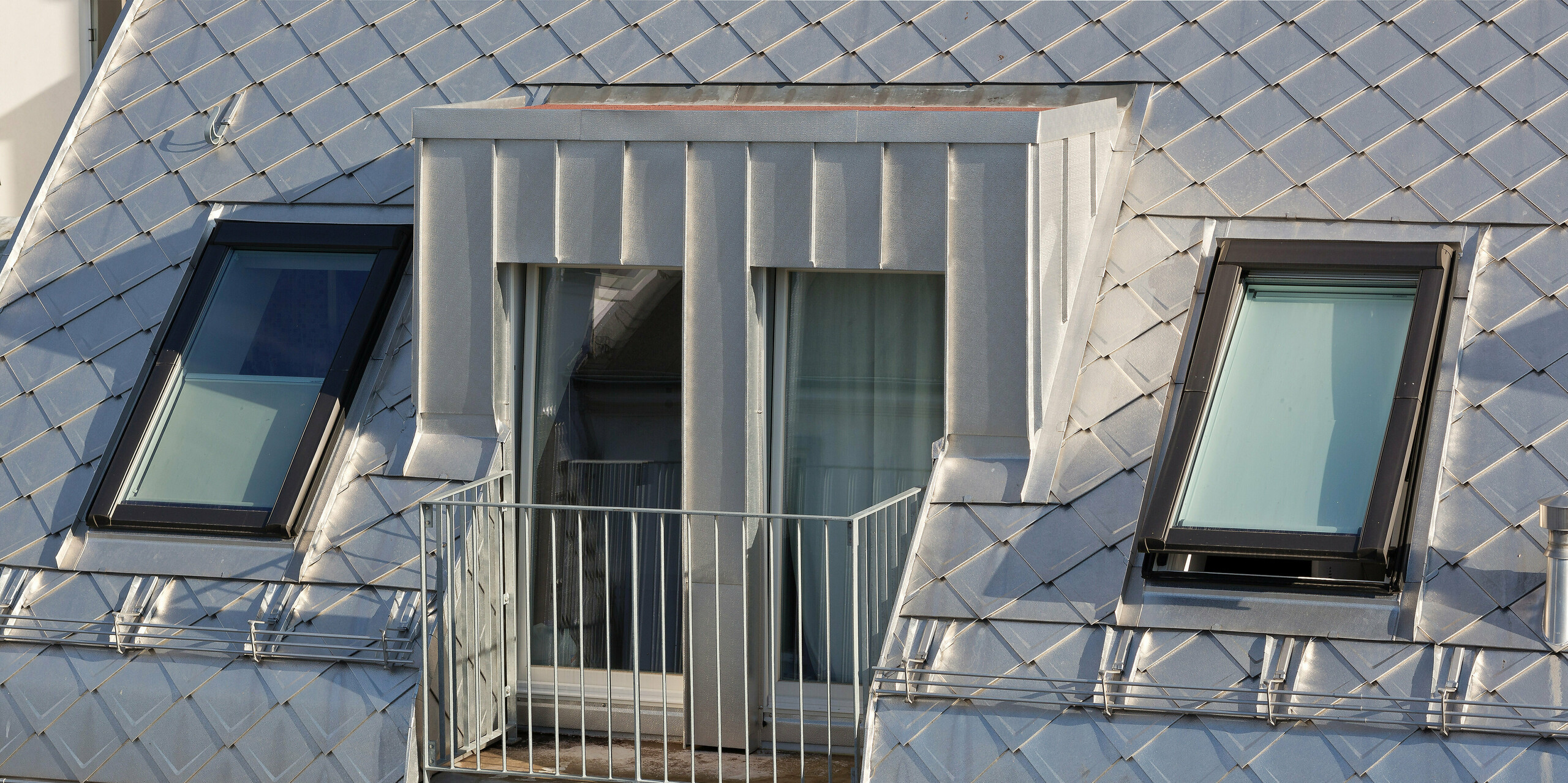 Das Dach dieses modernen Wohngebäudes in Hamburg wurde mit PREFA Dachrauten 29 × 29 in der Farbe Naturblank gedeckt. Dadurch erhält es eine auffällige, metallische Optik. Besonders hervorzuheben ist der charmante Balkon, der sich harmonisch in das Design des Daches einfügt.