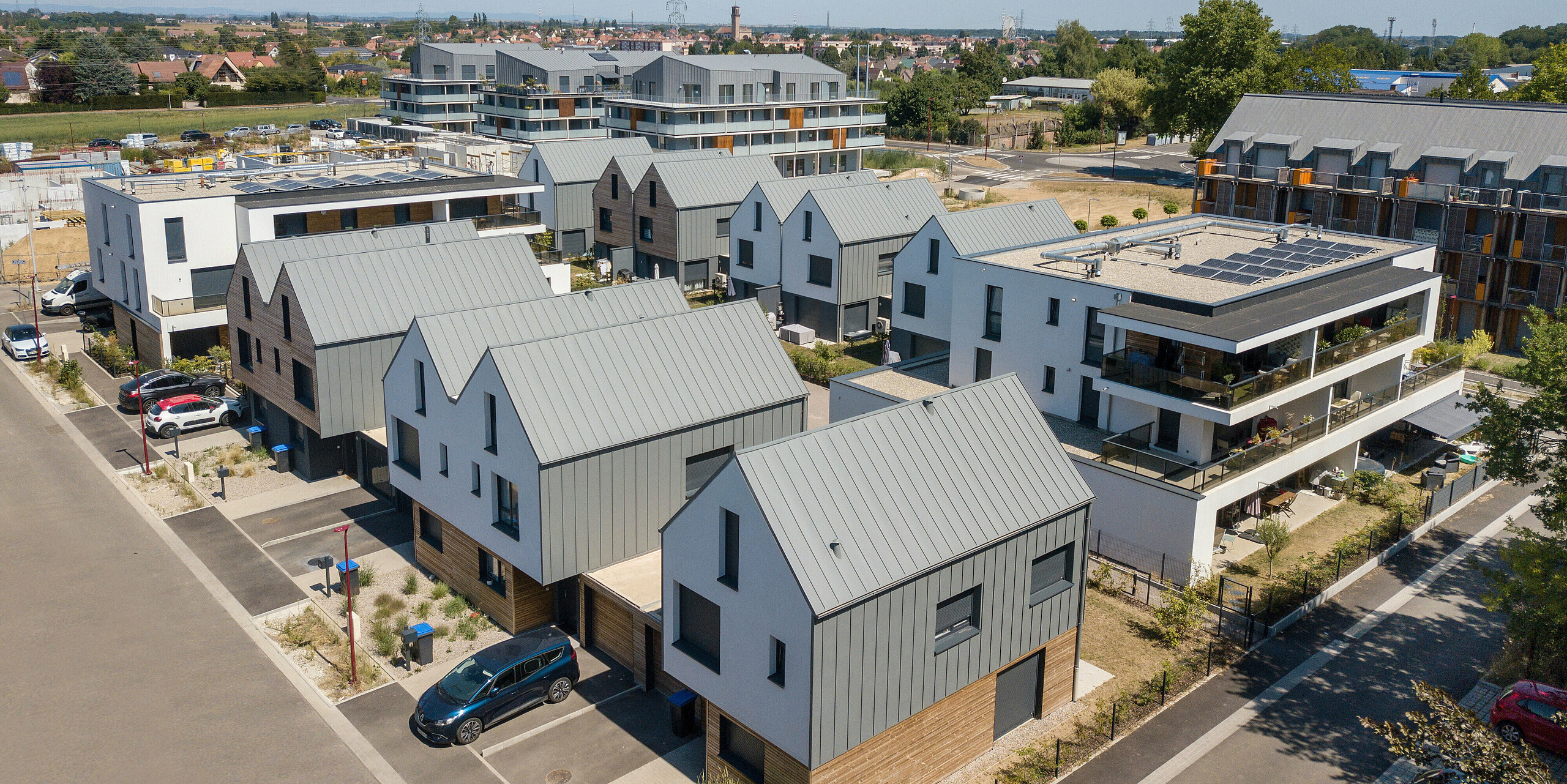Le joint debout PREFALZ en gris souris s'étend sur les façades et les toits à pignon d'un lotissement mitoyen à Mundolsheim. Les coques uniformes du bâtiment en aluminium créent une image globale harmonieuse.