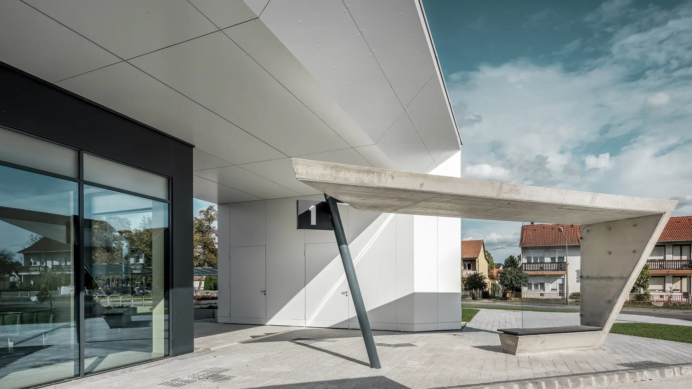 Entrée de la gare routière de Lenti ; la sous-face de la toiture est revêtue de panneaux composites en aluminium PREFABOND de PREFA en blanc pur, tandis que les éléments de façade au niveau des portes d'entrée et des vitrines sont revêtus de P.10 blanc pur.