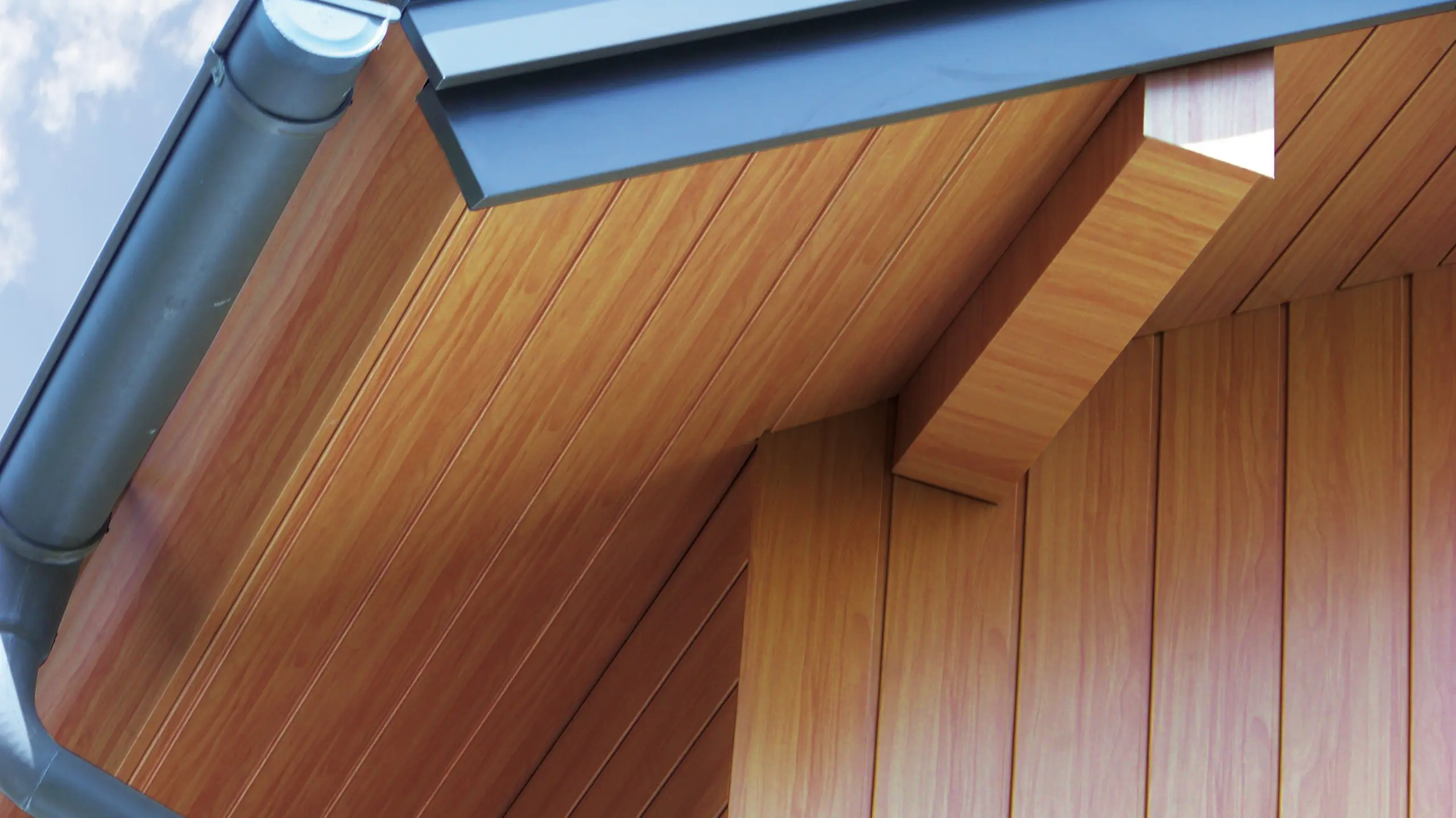 Intradosso del tetto rivestito con doghe di rivestimento PREFA di colore legno chiaro in alluminio.