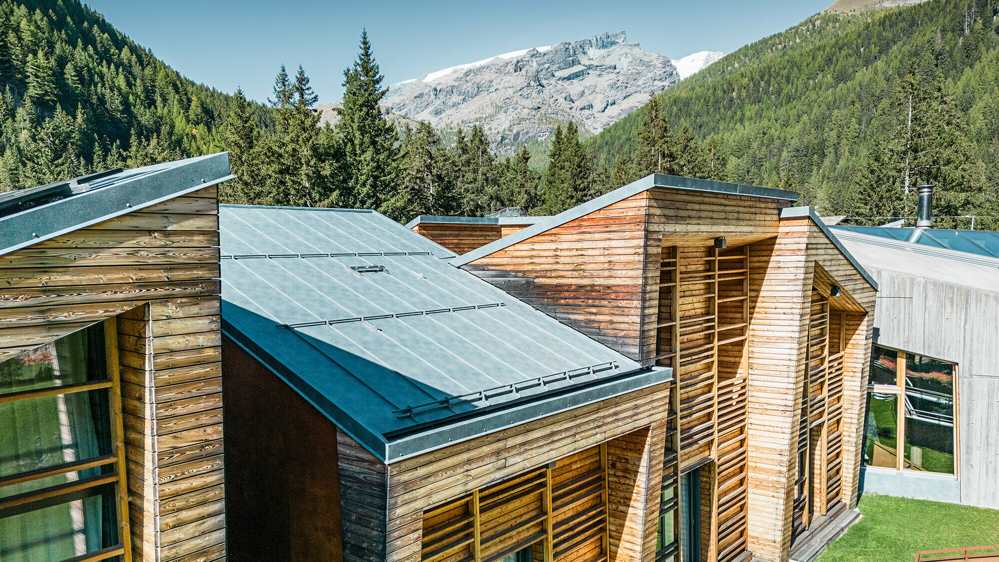 Dettaglio laterale della copertura, la facciata in legno e le lastre Prefalz posate con cura sono ben visibili.