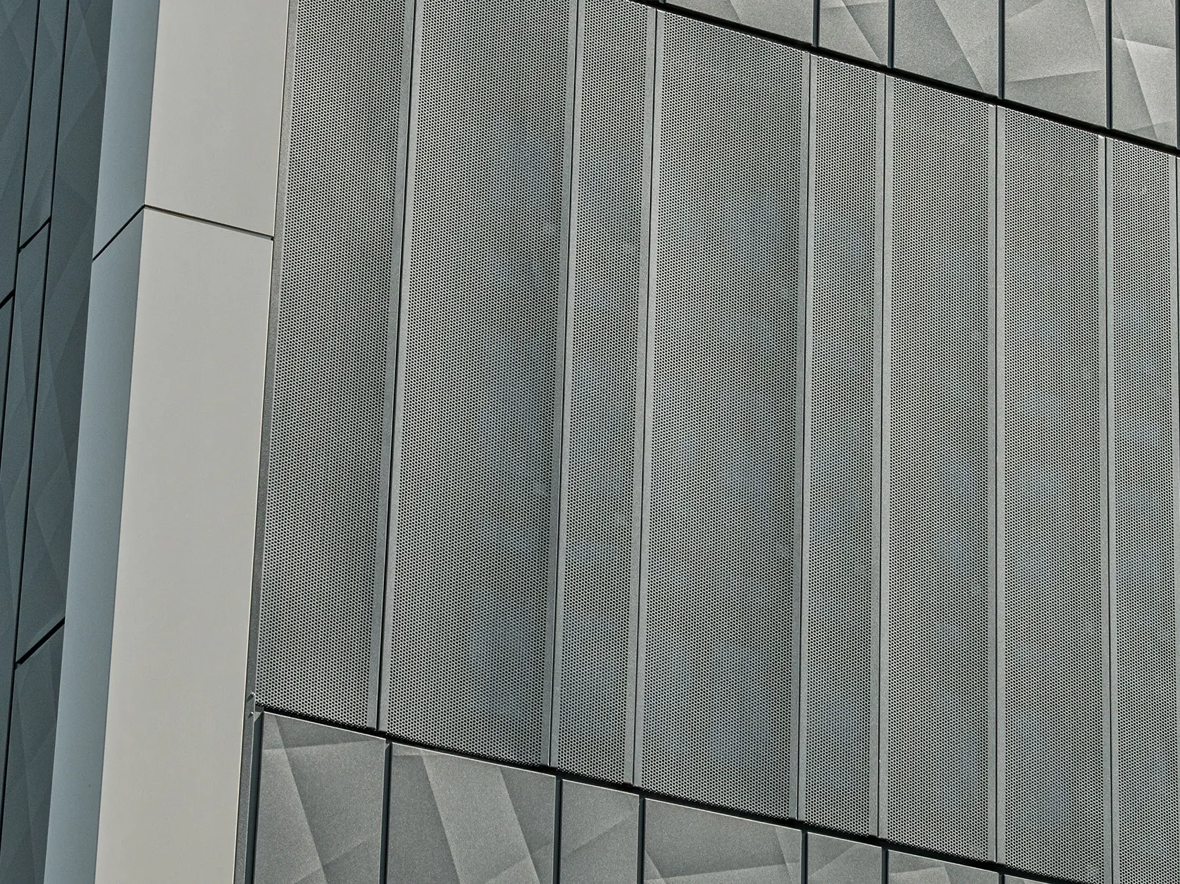 Vue de la façade d'un magasin Eurospar à Rohrbach avec des bardages PREFA Siding.X et des bardages perforés de couleur anthracite. Les éléments Siding.X présentent un motif de joints géométrique vivant, tandis que les bardages perforés offrent une structure moderne et perméable à l'air.