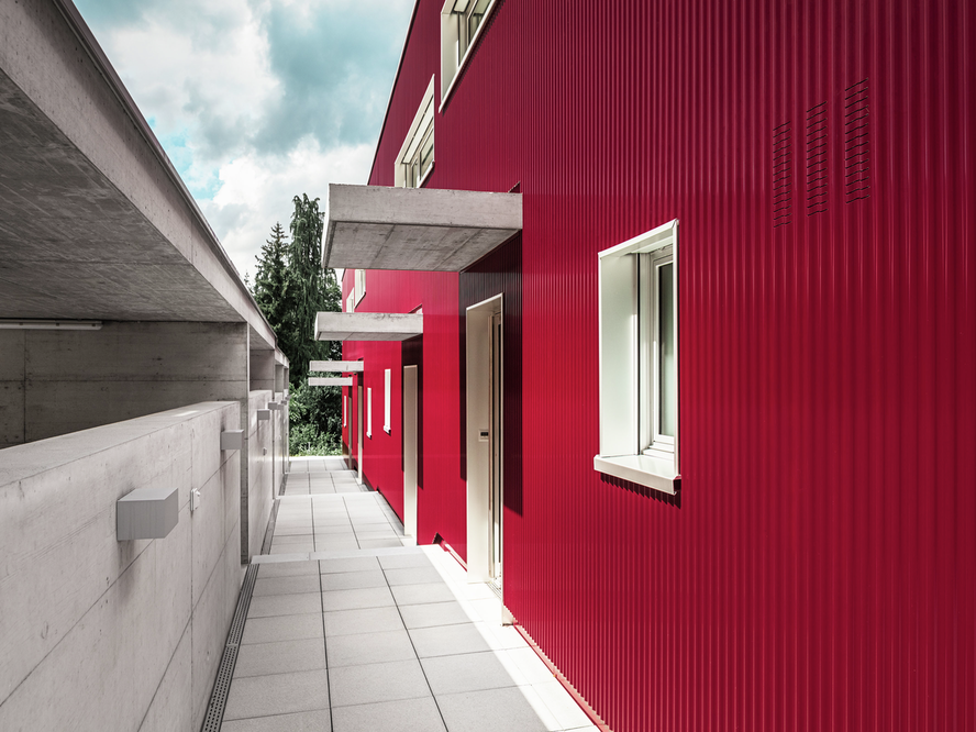 Vista laterale della facciata esterna dell'edificio residenziale sul Lago di Zurigo in Svizzera, rivestita con il profilo ondulato PREFA nel colore rosso vino