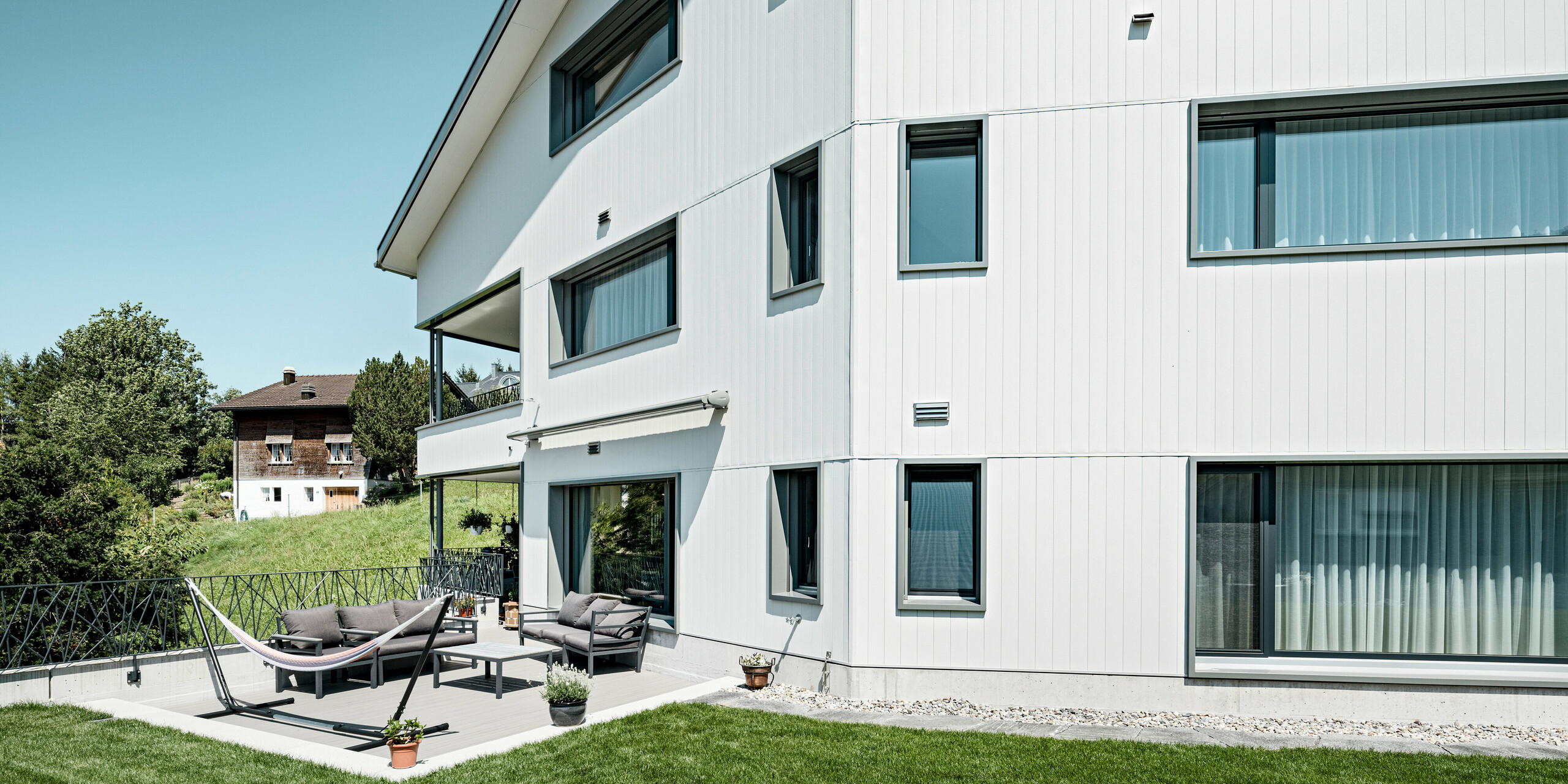 PREFA Sidings in P.10 Steingrau bzw. P.10 Prefaweiß an den Fassaden von zwei benachbarten Mehrfamilienhäusern in Weissbad, Schweiz.