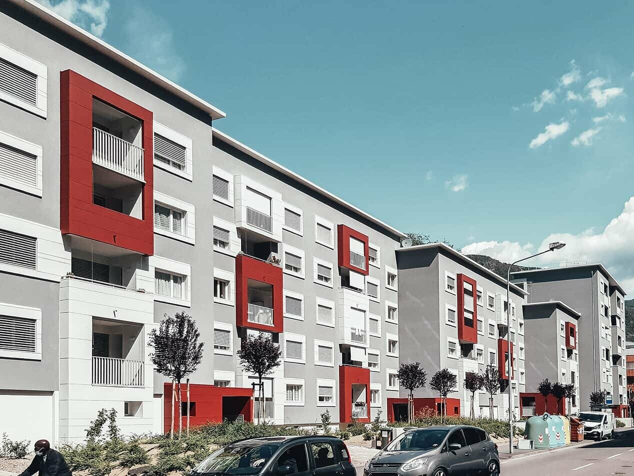 Schrägansicht eines Wohngebäudes im italienischen Bozen mit dem Fassadensystem Prefalz von PREFA in den Farben Oxydrot und Prefaweiß