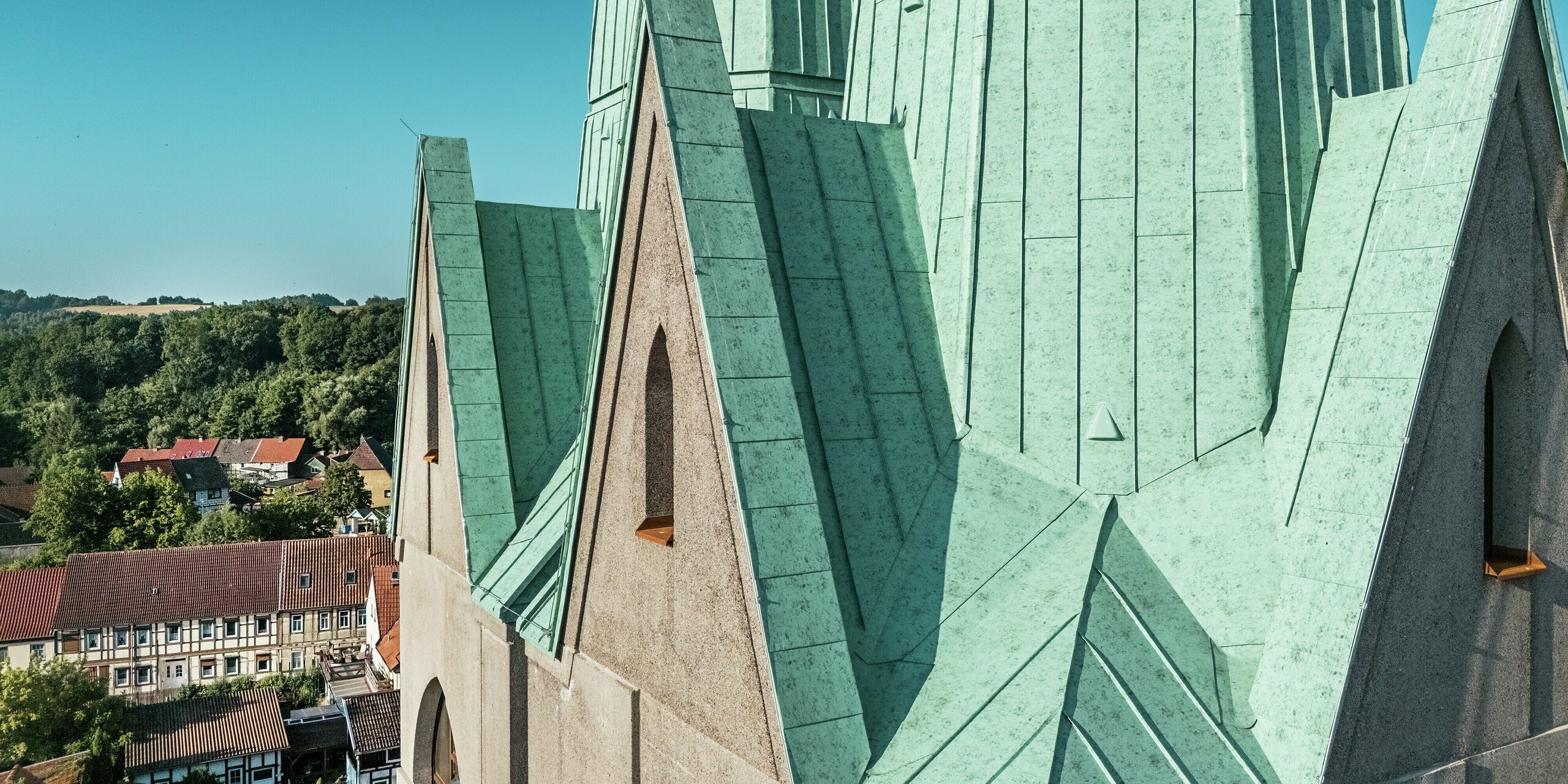 Détail du clocher nouvellement construit du Centre Touristique d'Ellrich : les joints précis réalisés en aluminium PREFALZ couleur Vert de gris P.10 attirent immédiatement le regard. La surface scintille au soleil et souligne la réinterprétation moderne de l'architecture historique. Robuste, durable et nécessitant peu d'entretien, le matériau PREFALZ, grâce à sa grande flexibilité de mise en œuvre, est parfaitement adapté aux toitures aux géométries complexes.