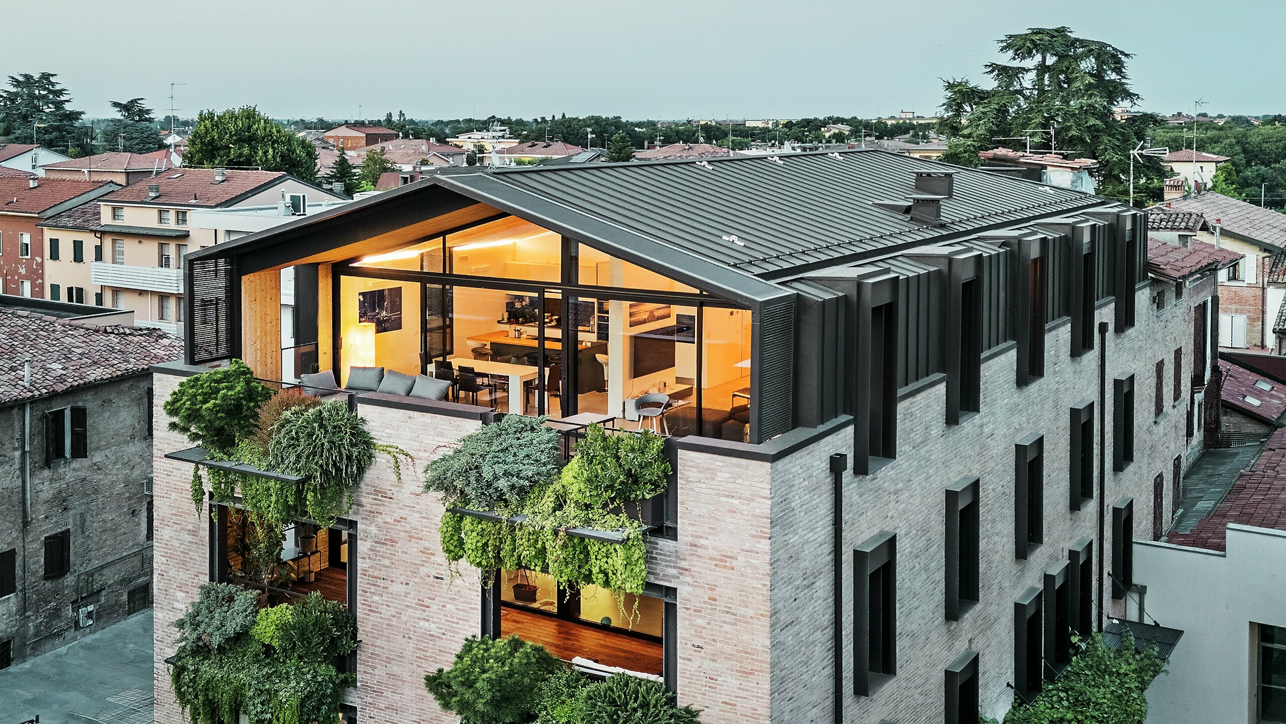 Nachhaltiges Wohnhaus in Italien mit PREFALZ Aluminiumdach und begrünter Backsteinfassade.
