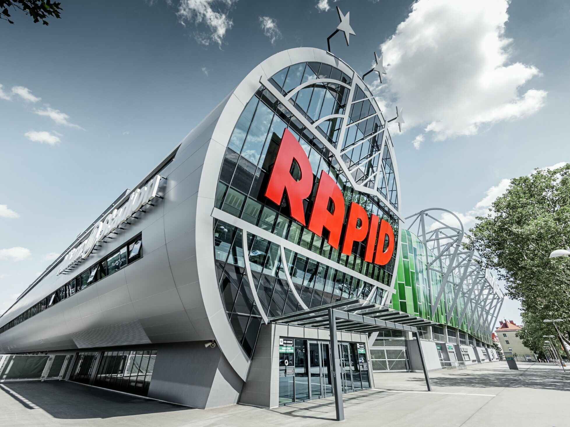 L’entrée de l’Allianz Stadion avec le grand logo du SK Rapid de Vienne ; le tube avec la grande façade vitrée est recouvert du panneau composite en aluminium PREFA couleur argent métallisé.