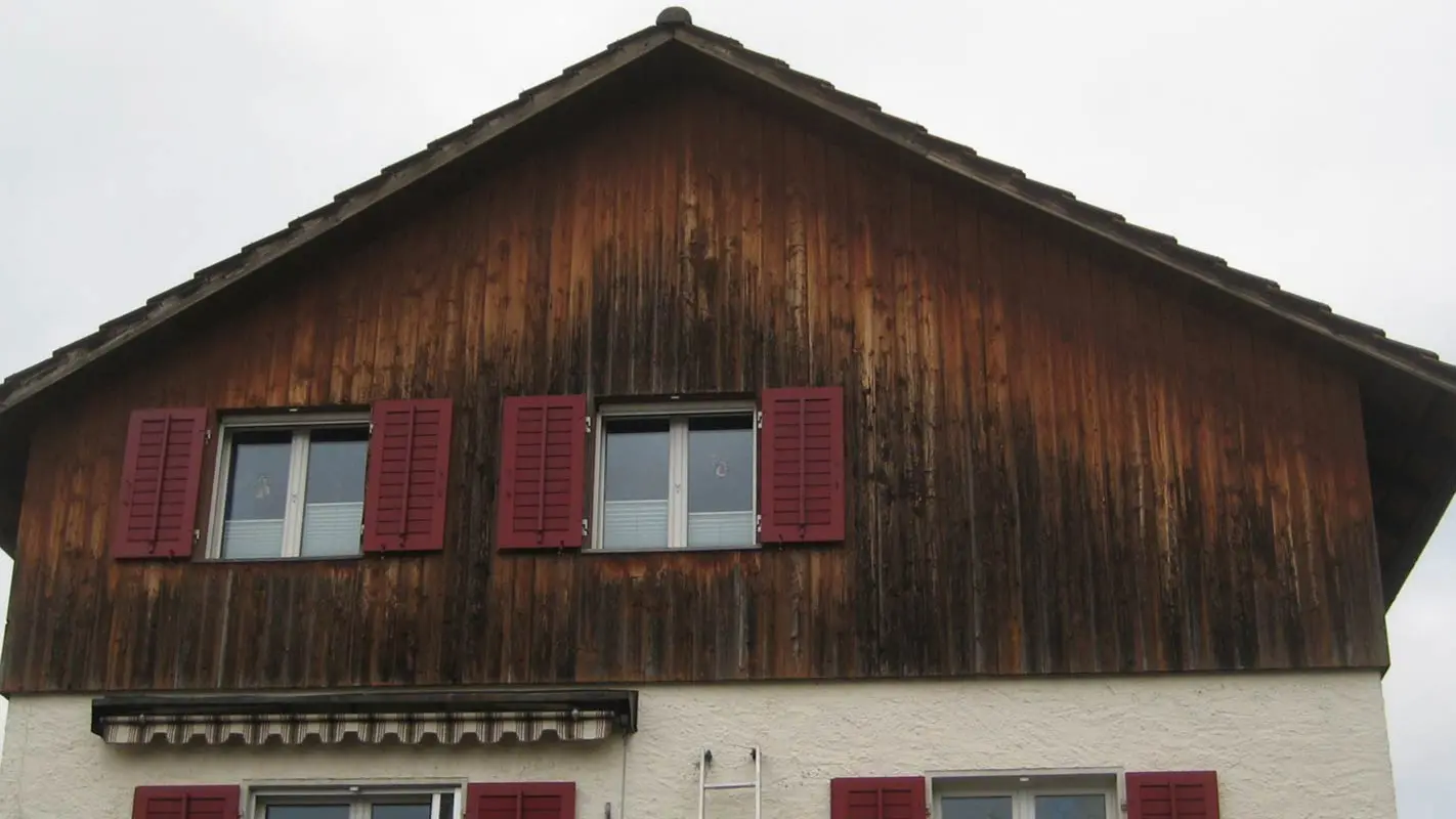Facciata con legno deteriorato prima della ristrutturazione con doghe di rivestimento PREFA