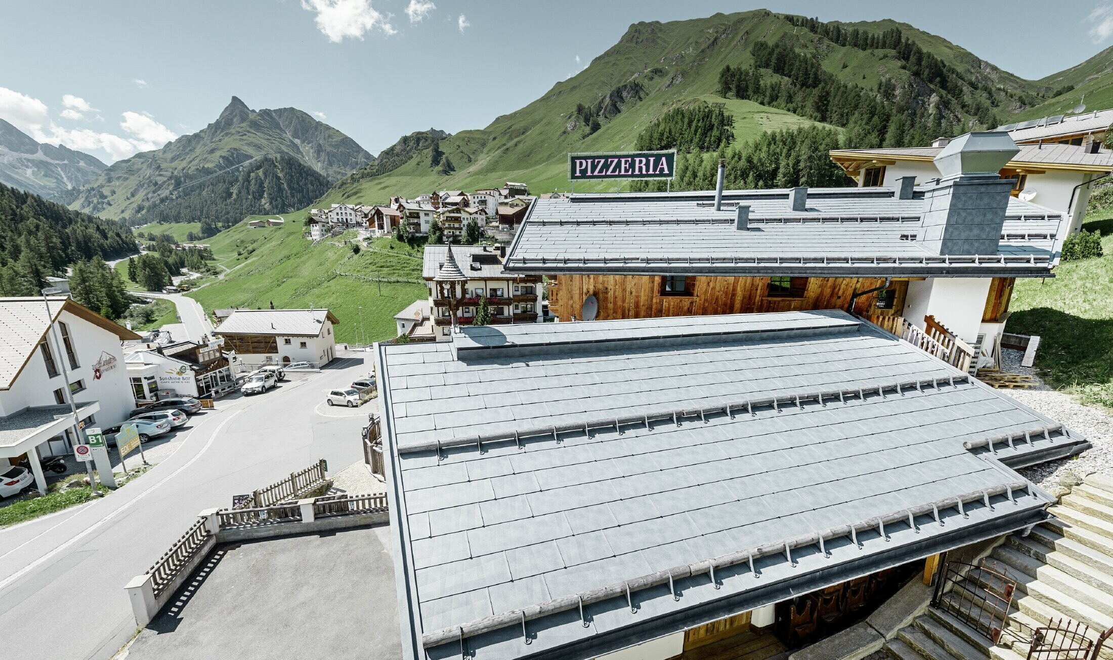 Restaurant Almrausch au cœur d’un décor de montagnes — Toiture PREFA réalisée avec des panneaux de toiture FX.12 gris pierre et dotée de tubes pare-neige