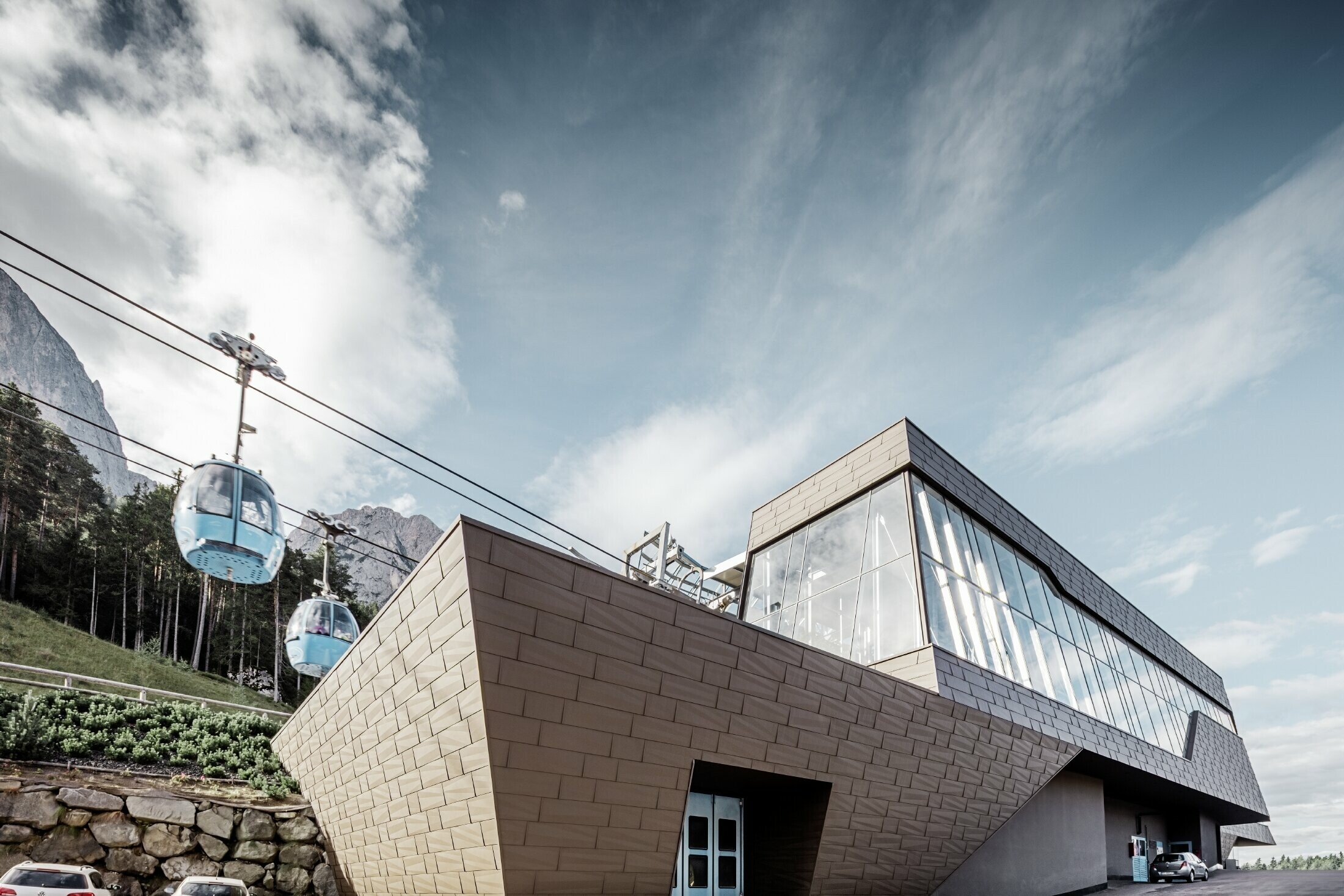 Stazione a valle della cabinovia dell'Alpe di Siusi, simile alle dolomiti sullo sfondo con bordi e superfici irregolari con una facciata in alluminio marrone di PREFA